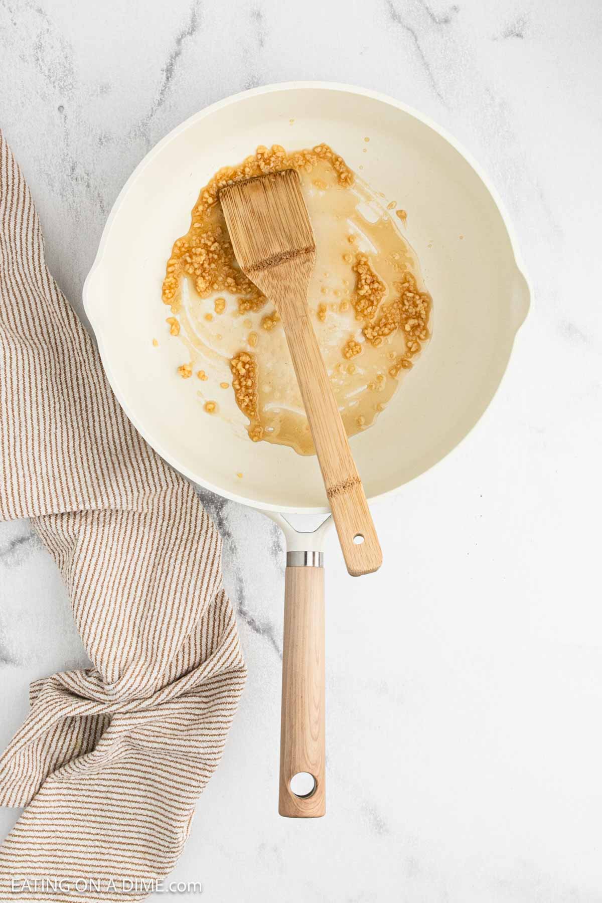 Oil and minced garlic in a large skillet with a wooden spatula.