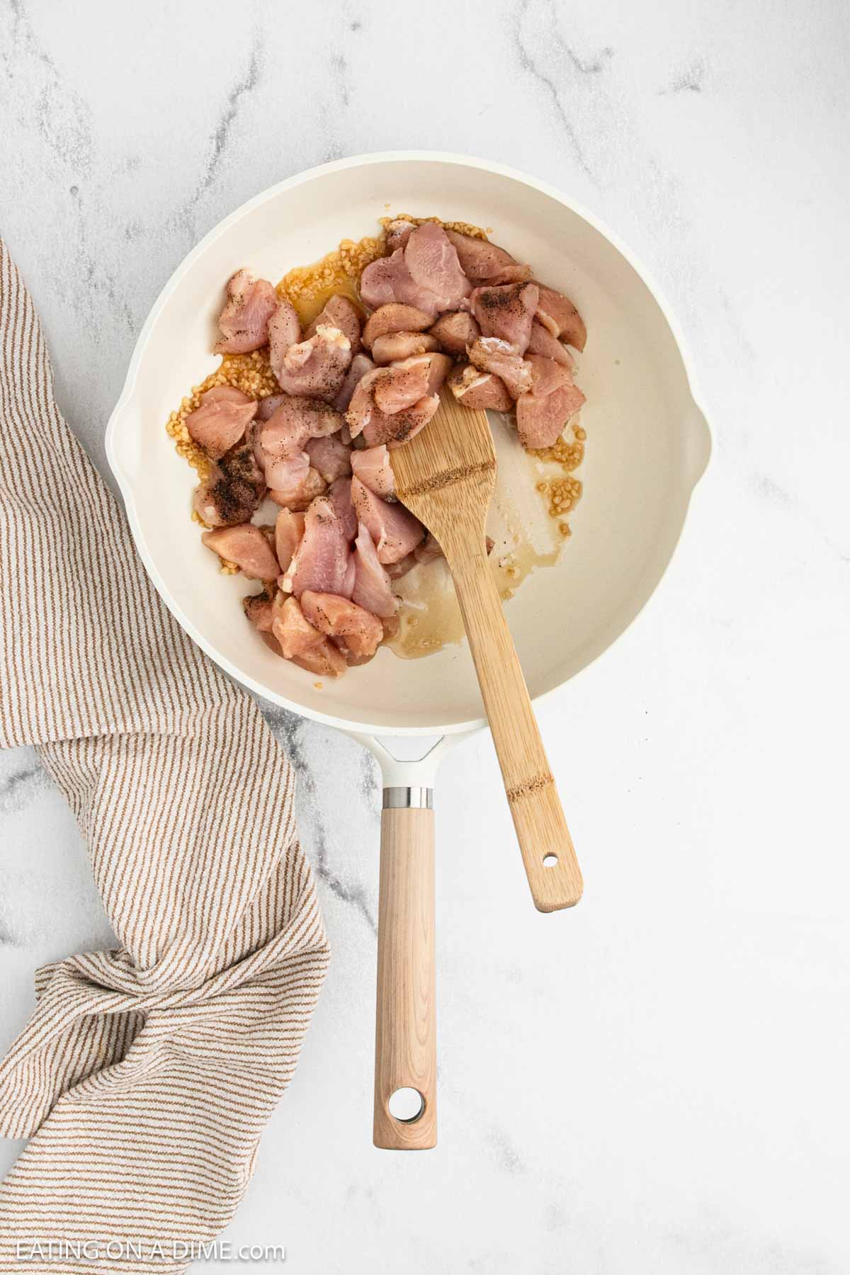 Diced seasoned raw chicken in a large skillet with the minced garlic.