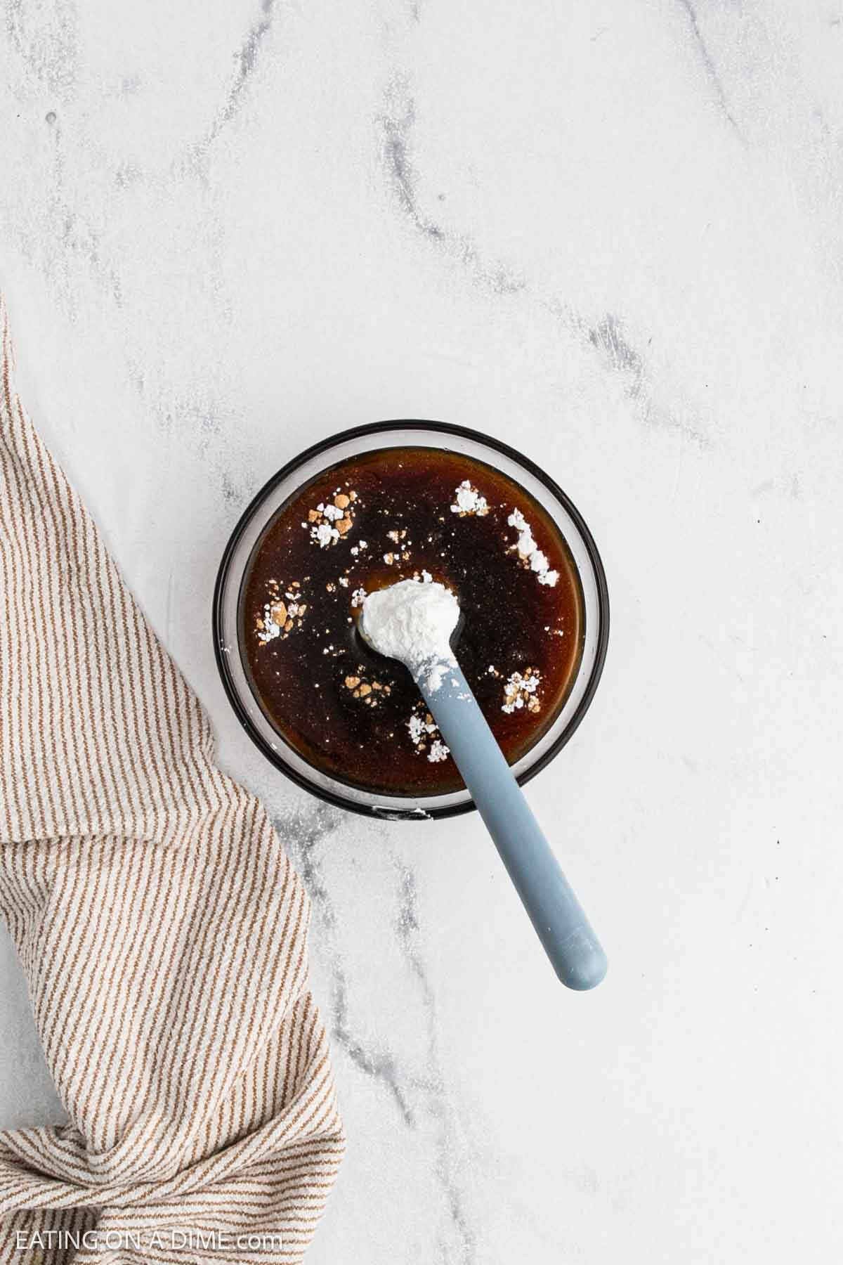 Combining the sauce ingredients in a bowl with a blue spatula.