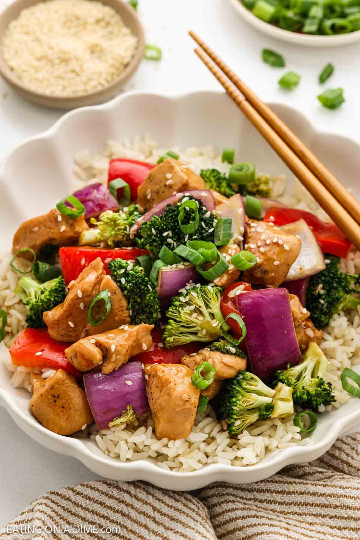 Teriyaki chicken and cooked broccoli, red onion, and red bell pepper in a bowl with rice.