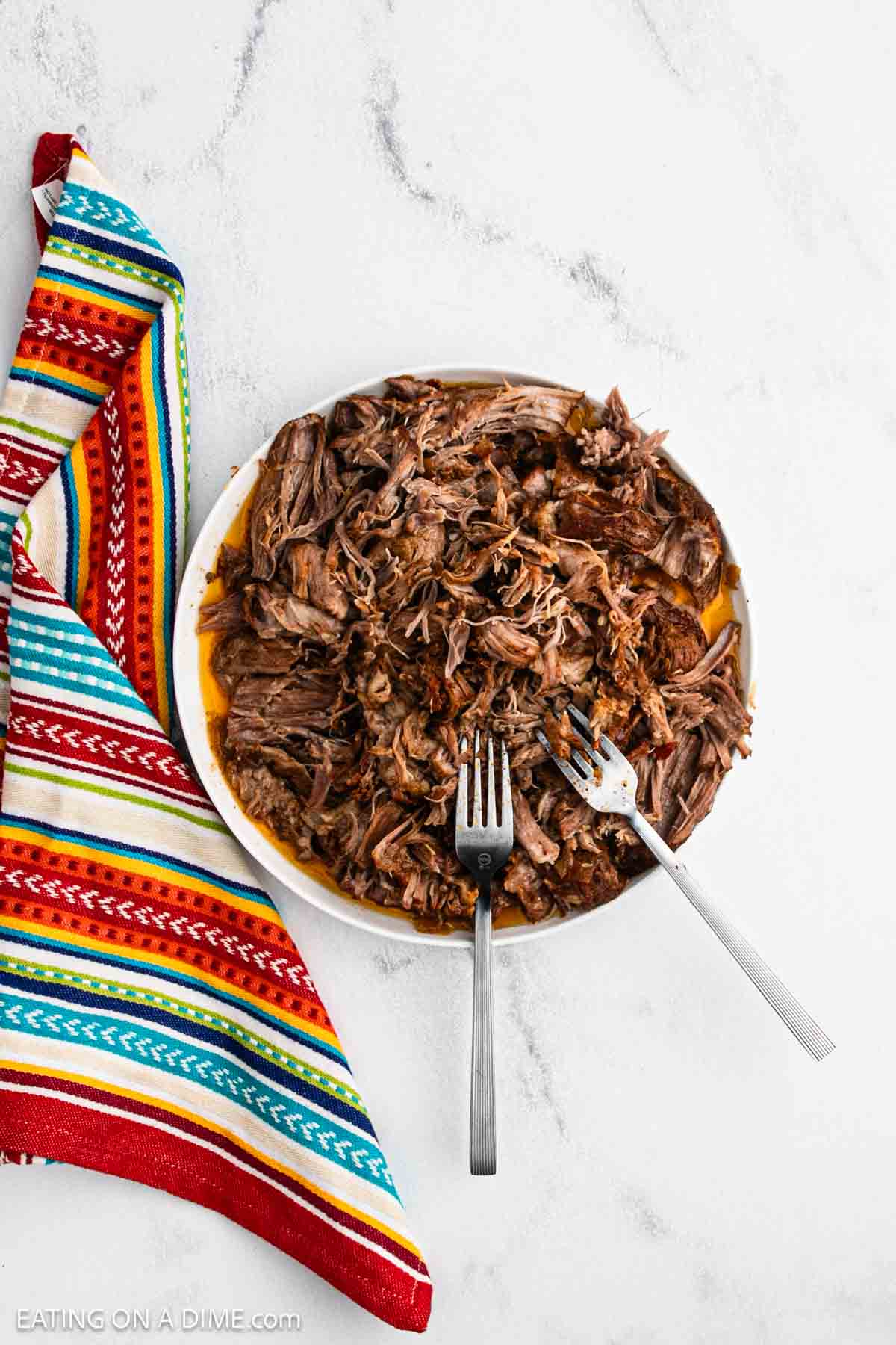 Shredded pork on a plate with two forks.
