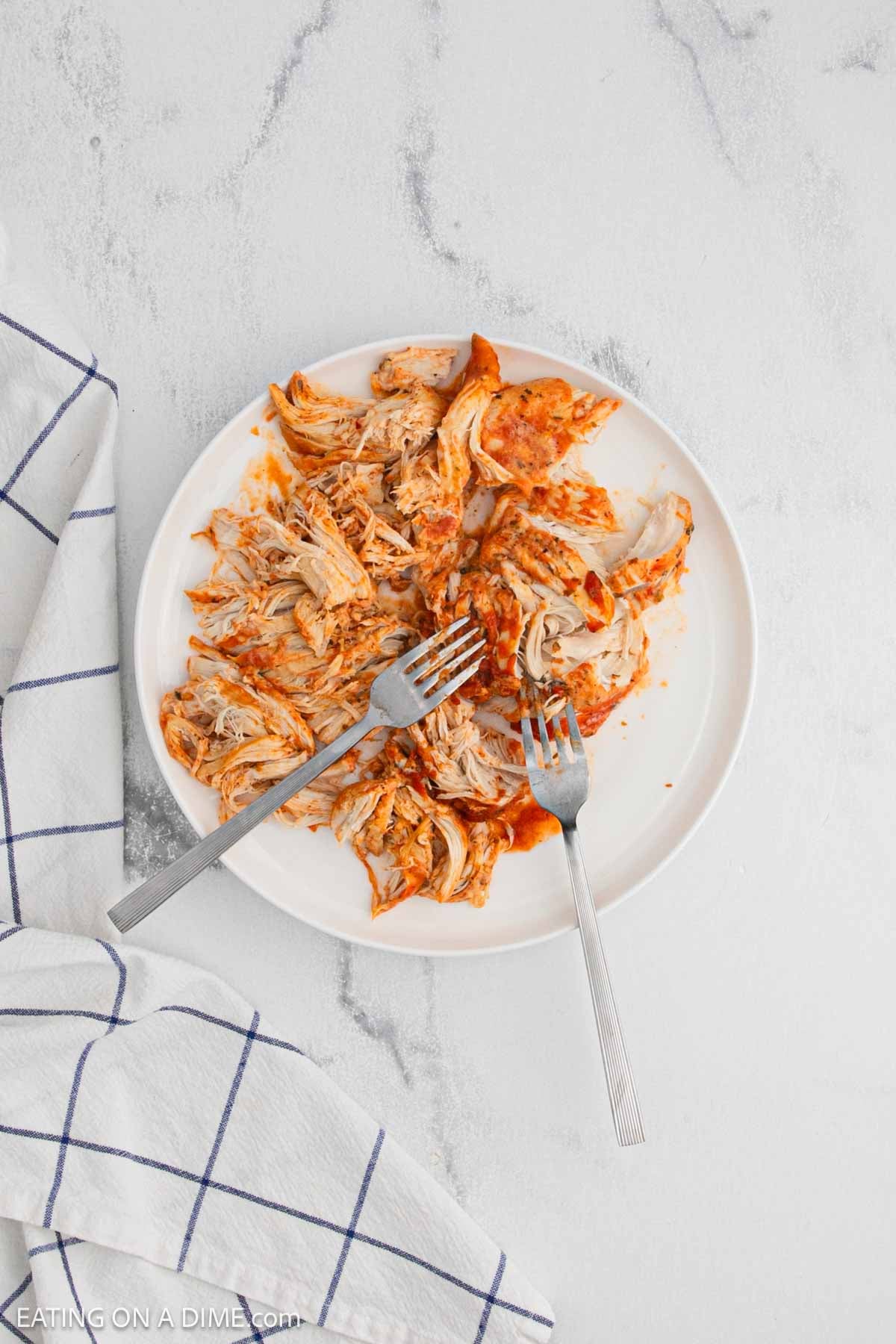 Shredded tomato sauce chicken on a plate with forks.