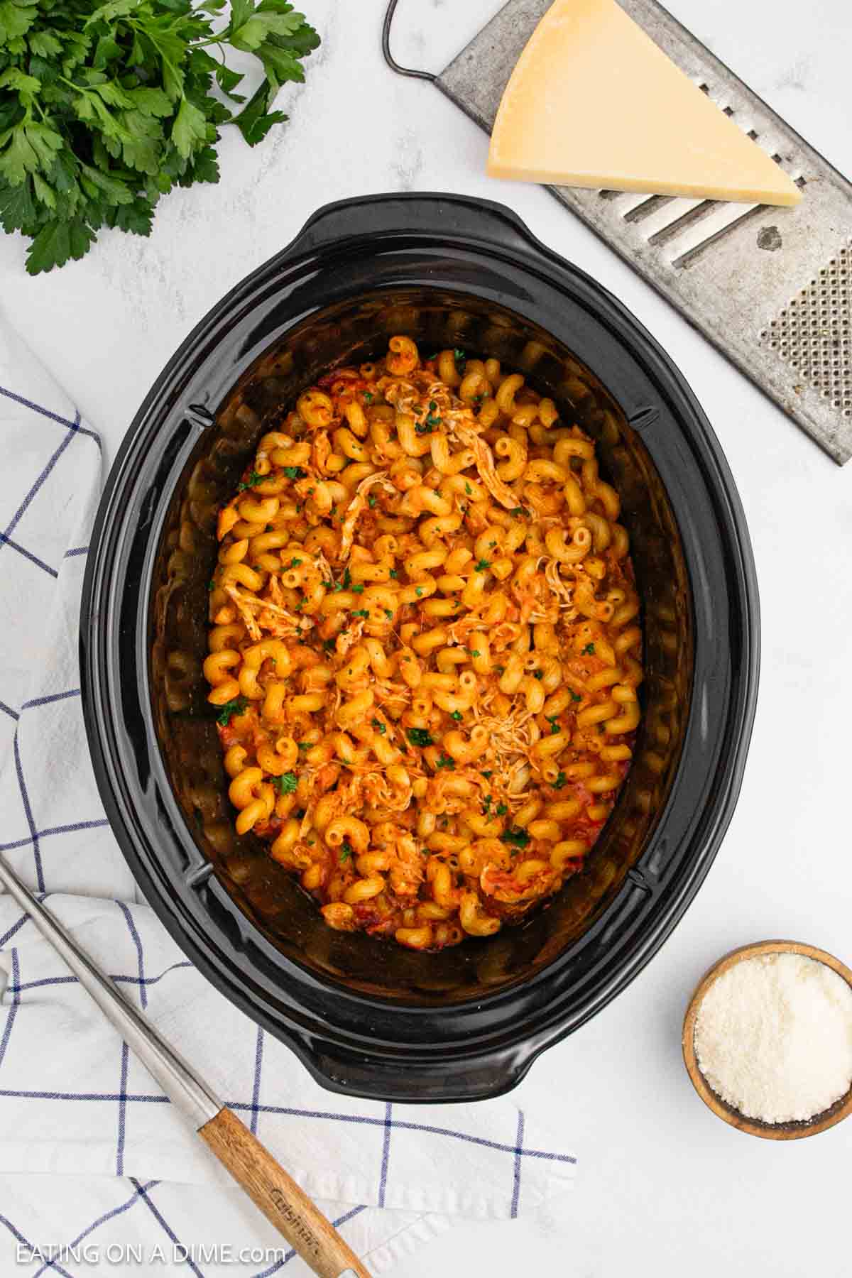 Shredded chicken and pasta covered in sauce in the slow cooker.