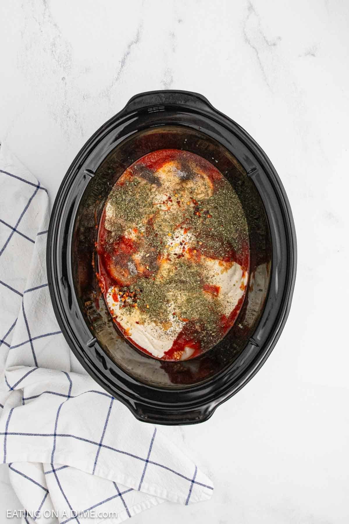 Spices, sauces and chicken placed in the slow cooker.