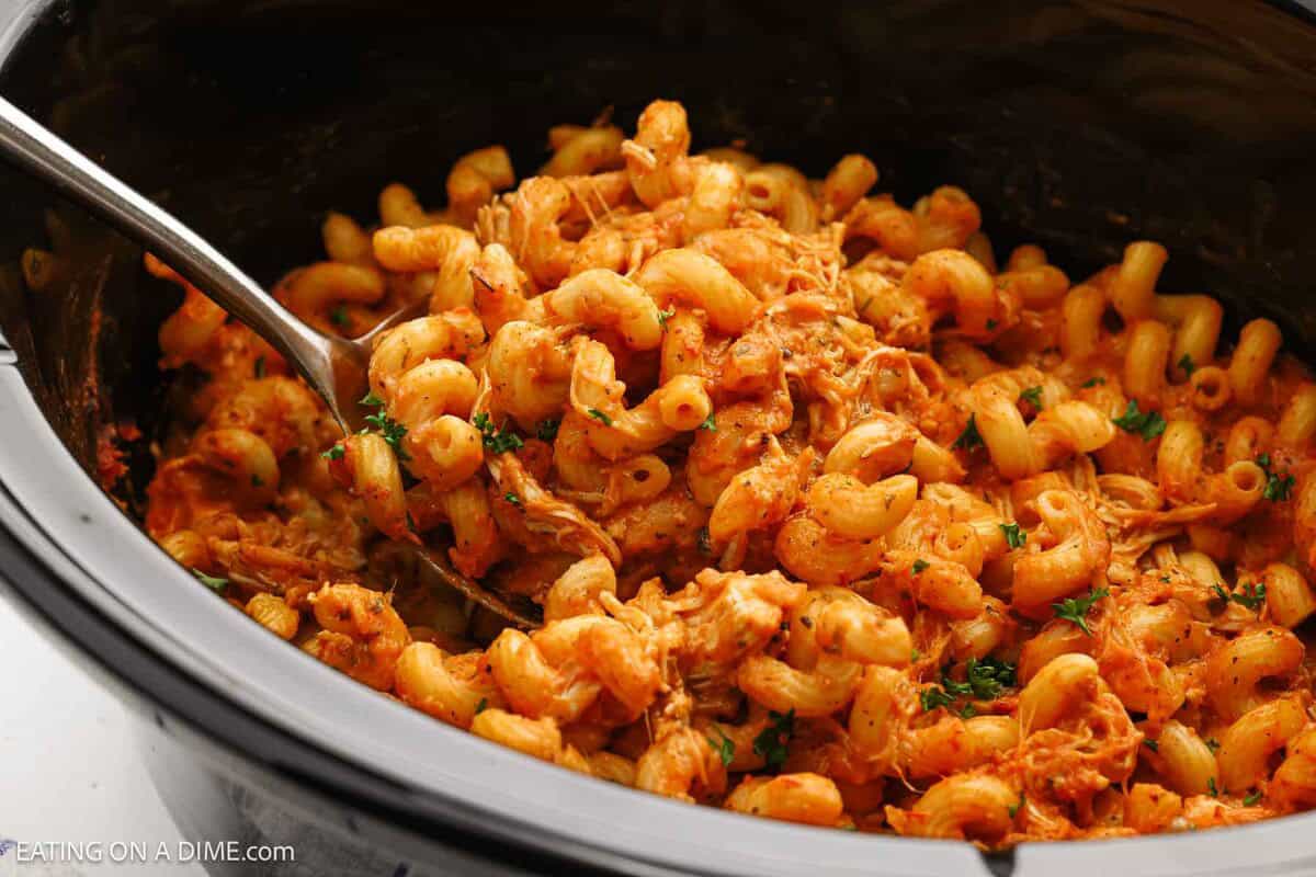 Creamy chicken pasta in the slow cooker with a serving of a silver spoon.