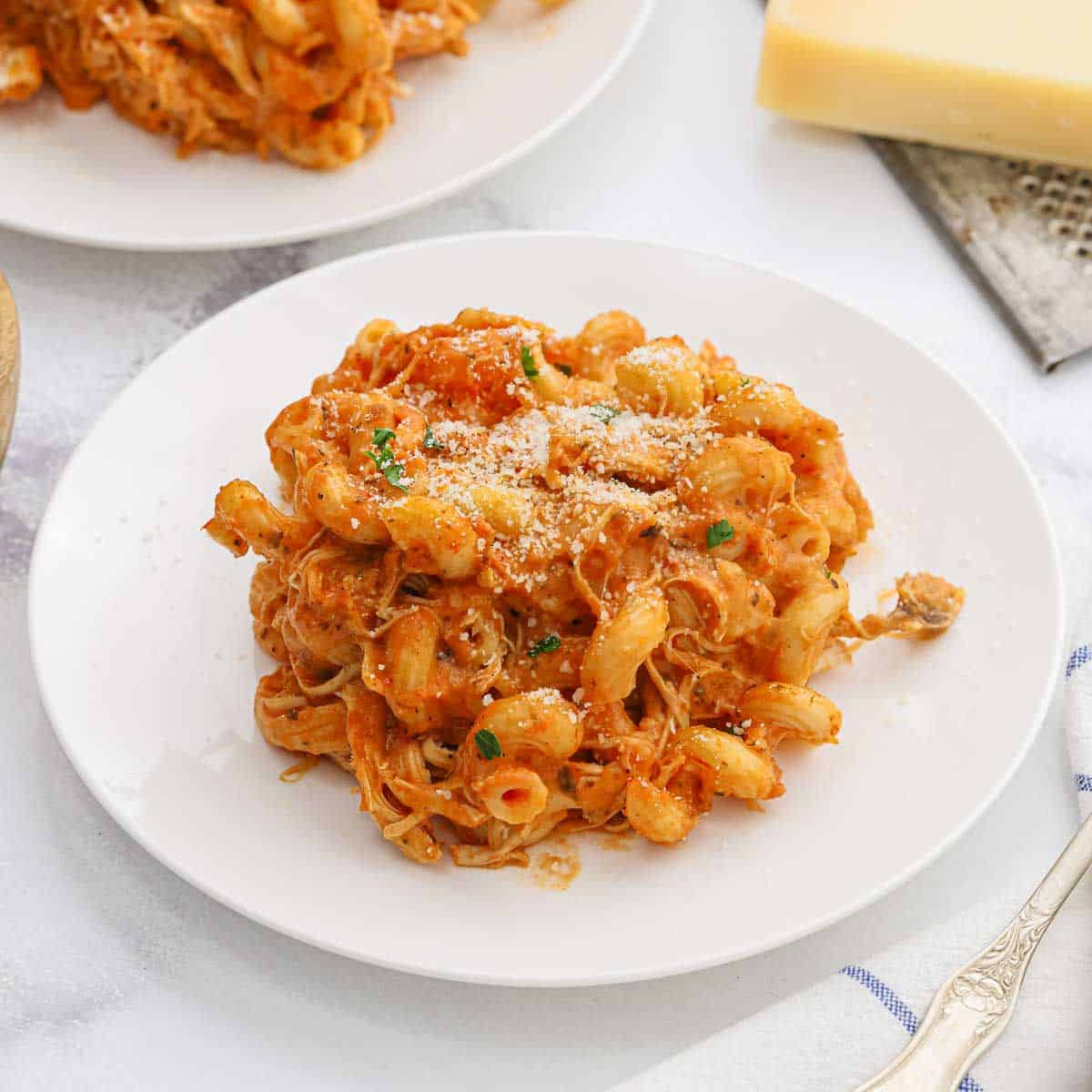 A serving of creamy chicken pasta on a white plate.