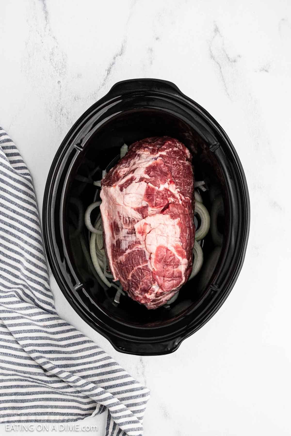 Pork should placed in the crock pot on top of slice onions.