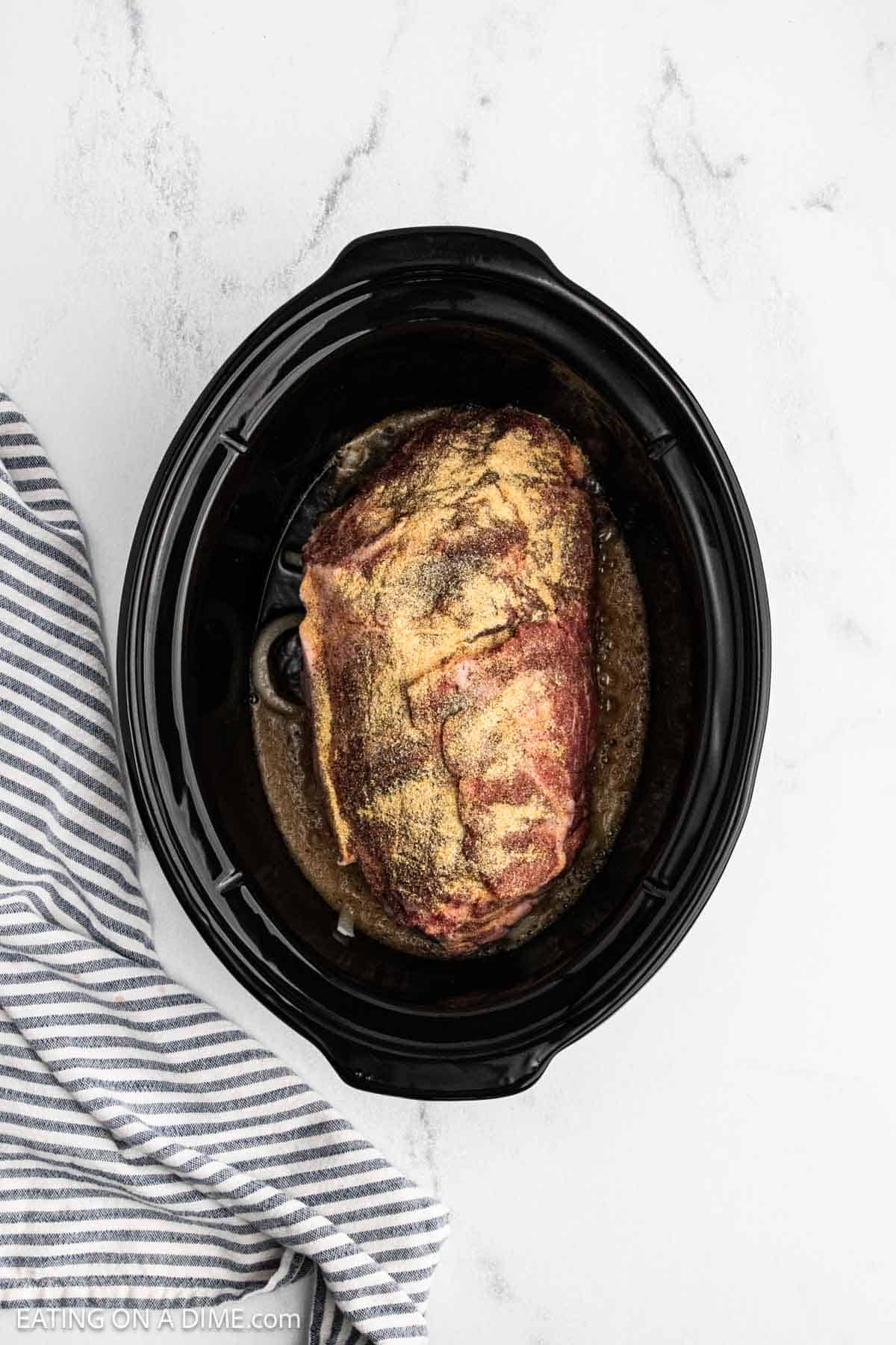 Seasoned pork should in the crock pot on top of slice onions and the liquid.