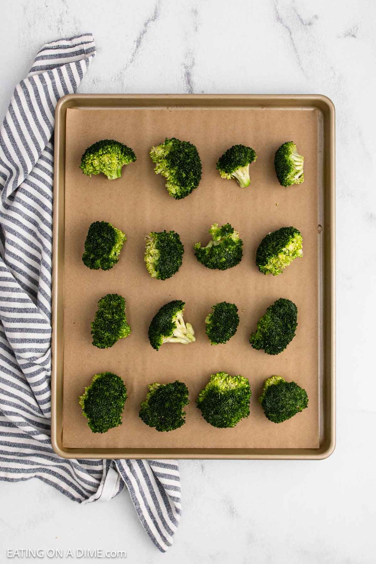 Fresh broccoli crowns placed on a baking sheet lined with parchment paper.
