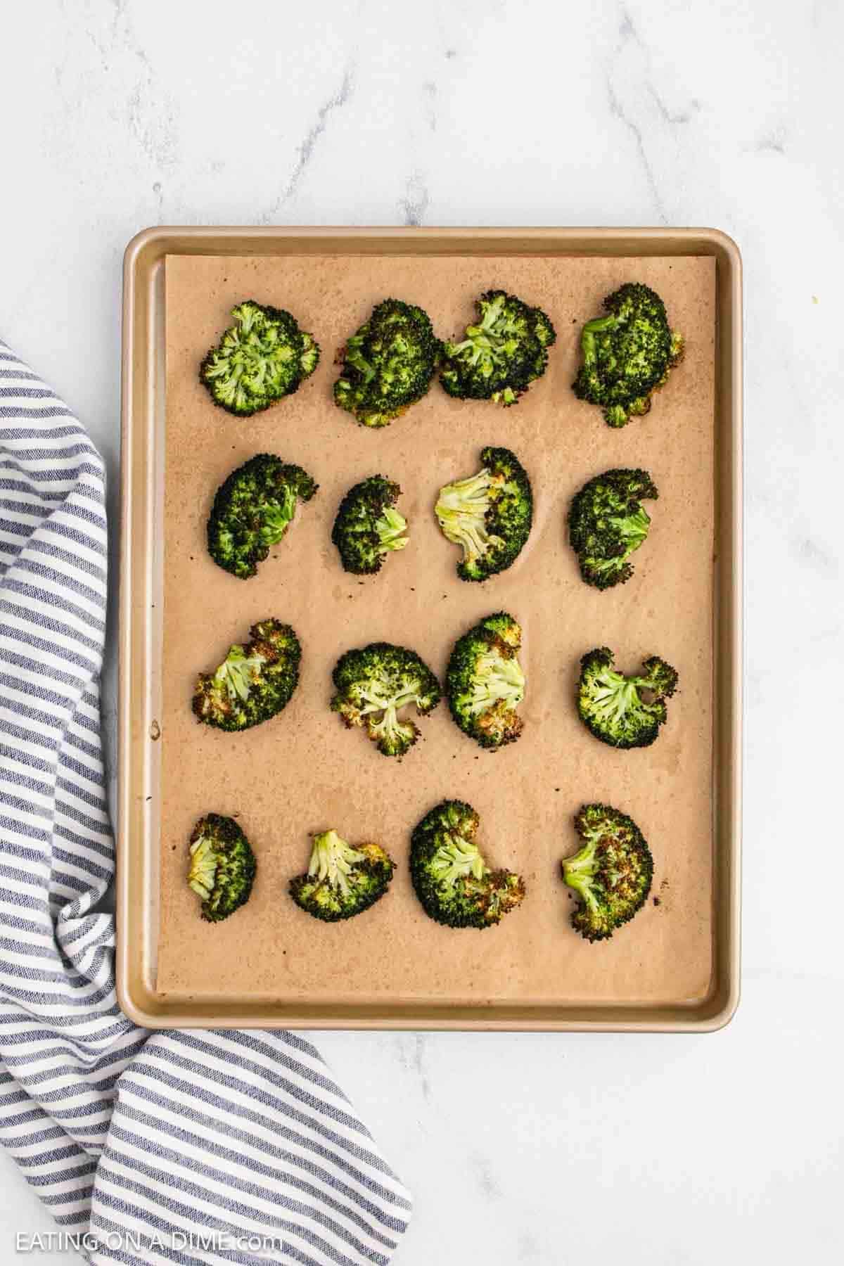 Roasted broccoli on a baking sheet lined with parchment paper.