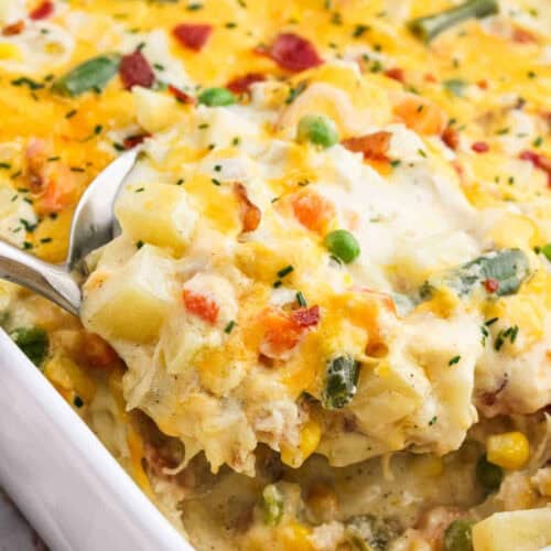 Baked casserole mixture of cheese, diced potatoes and more all in a white casserole dish.