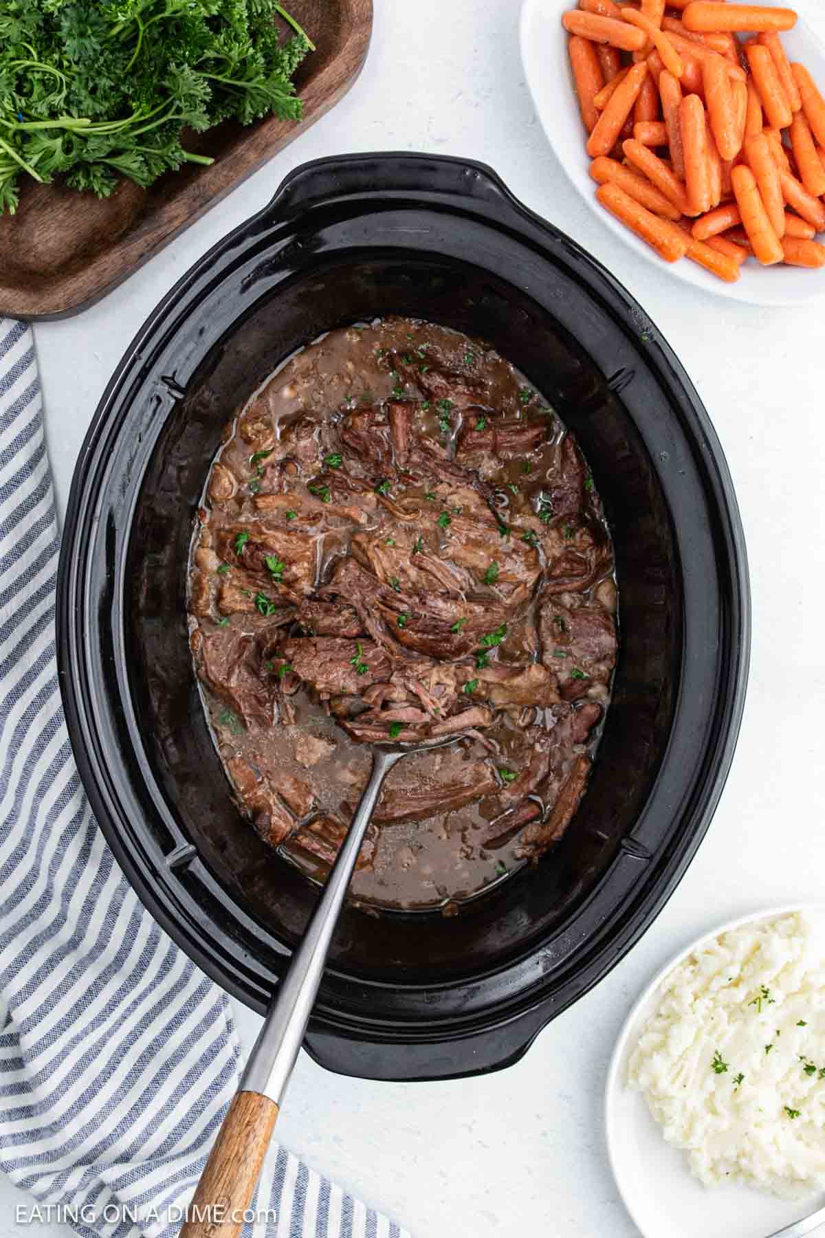 Shredded roast in gravy in the slow cooker.