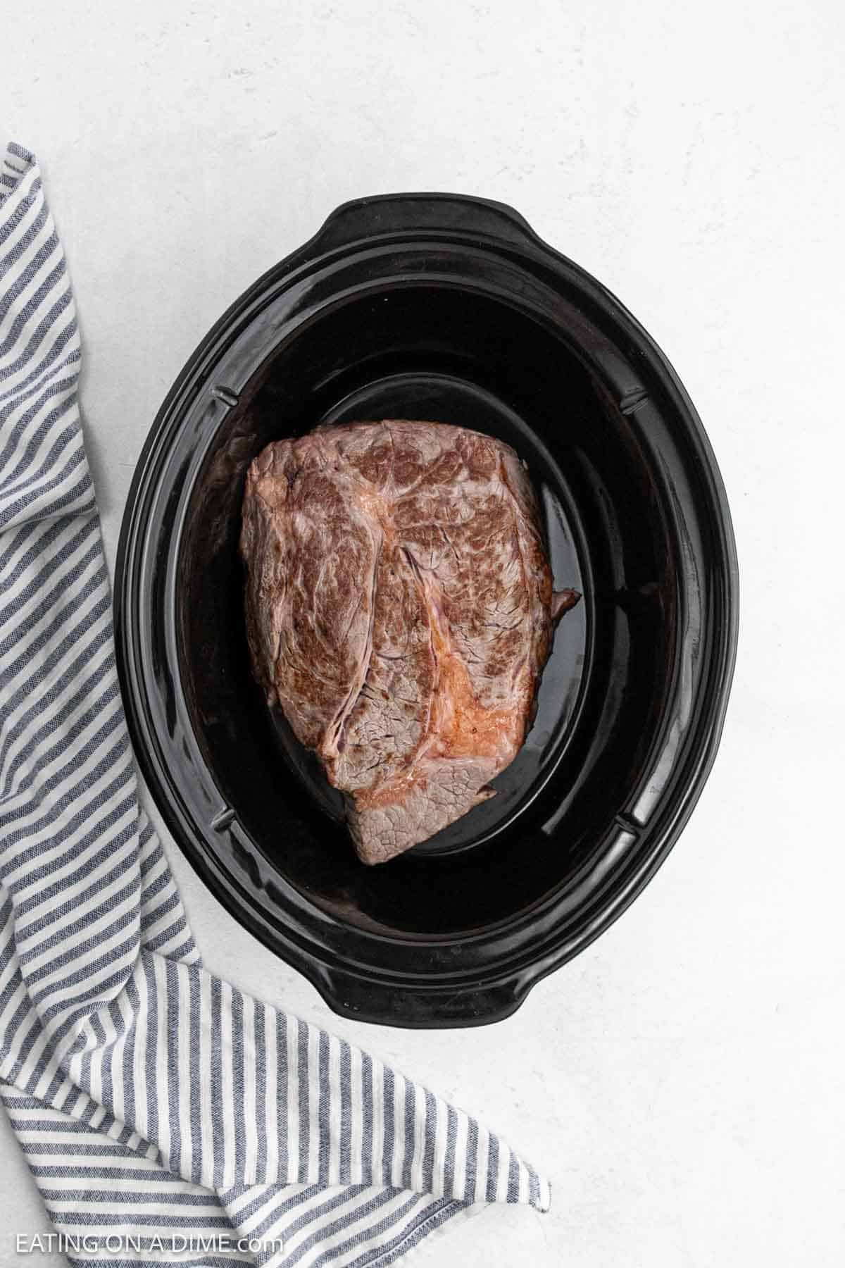 Seared roast placed in the slow cooker.