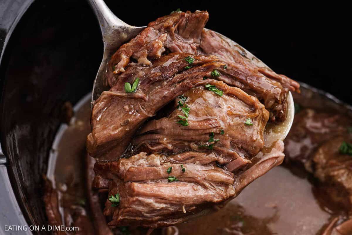 A serving of shredded roast and gravy on a spatula. 
