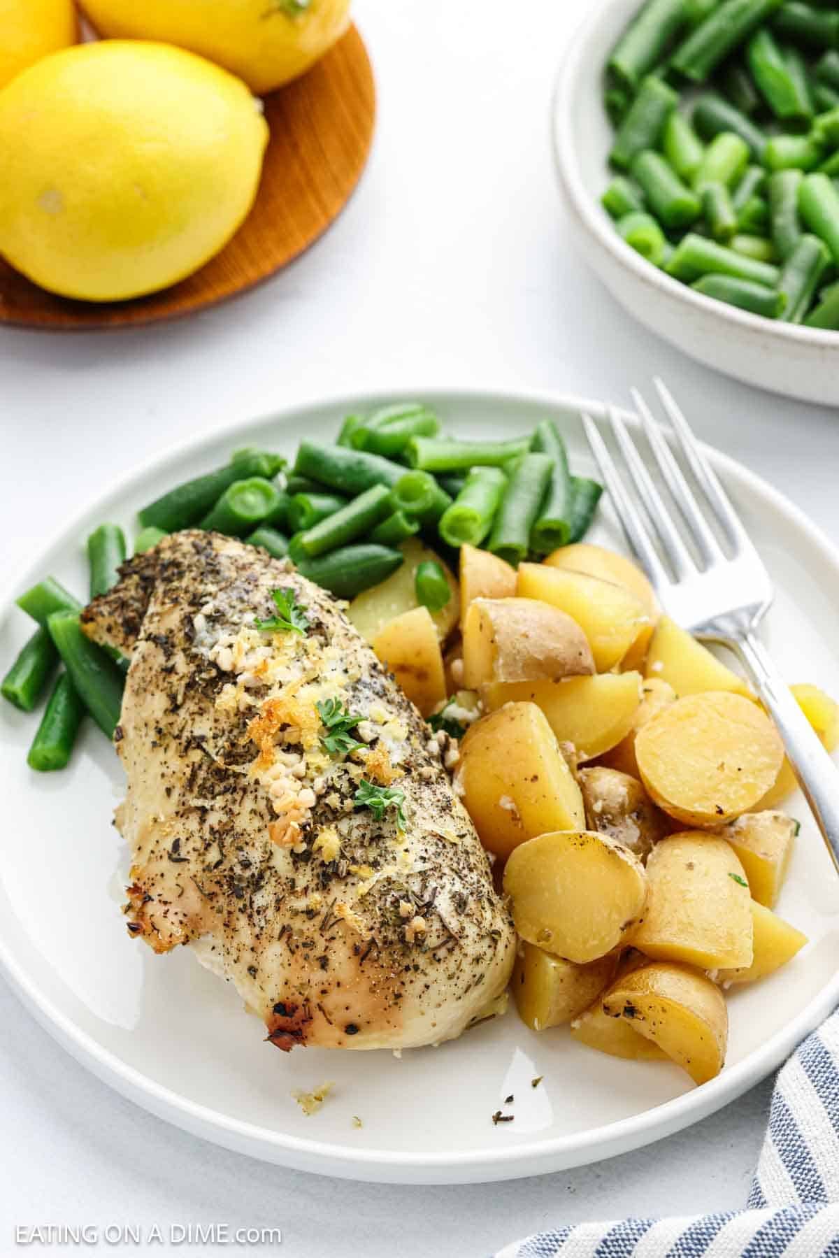 A serving of seasoned chicken breast, potatoes and carrots on a plate with a fork.