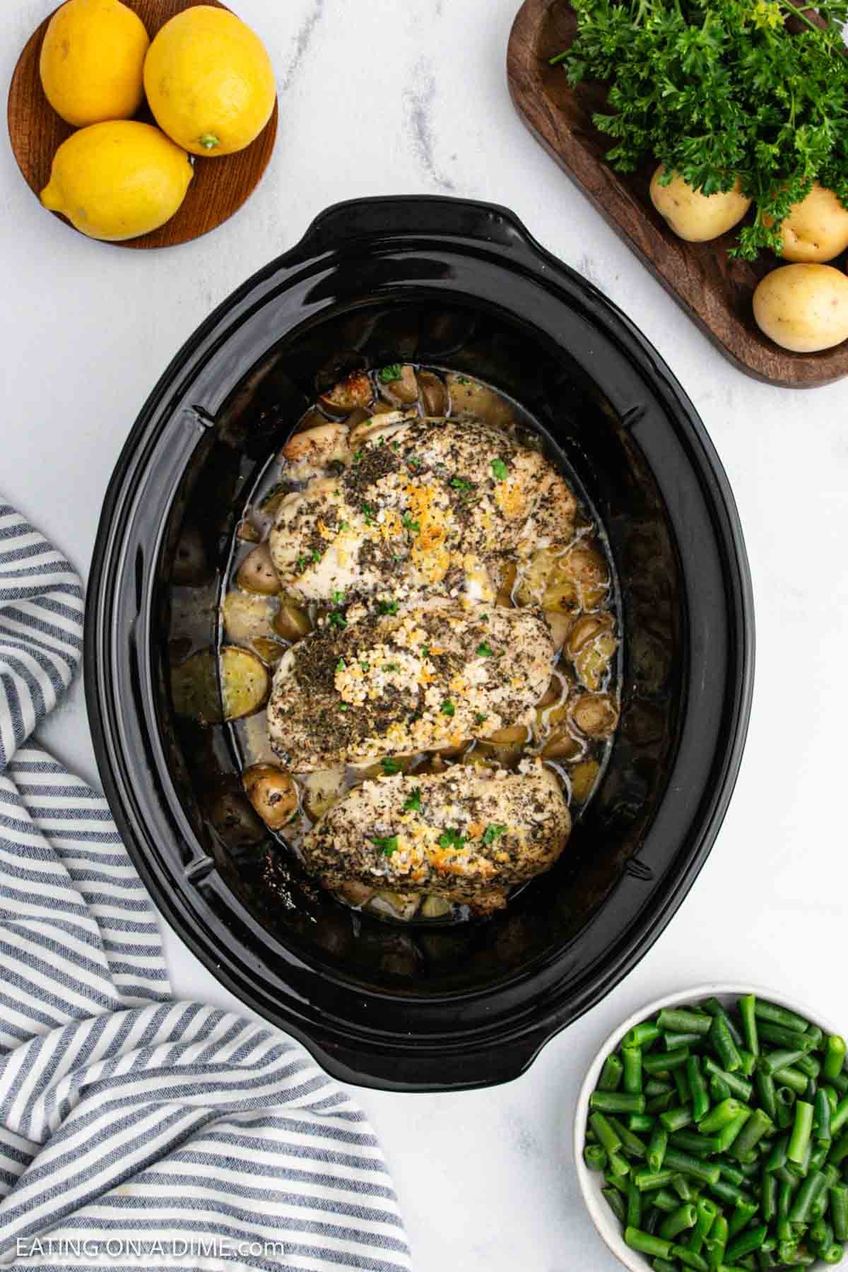 Cooked chicken breast and potatoes in liquid in the crockpot.