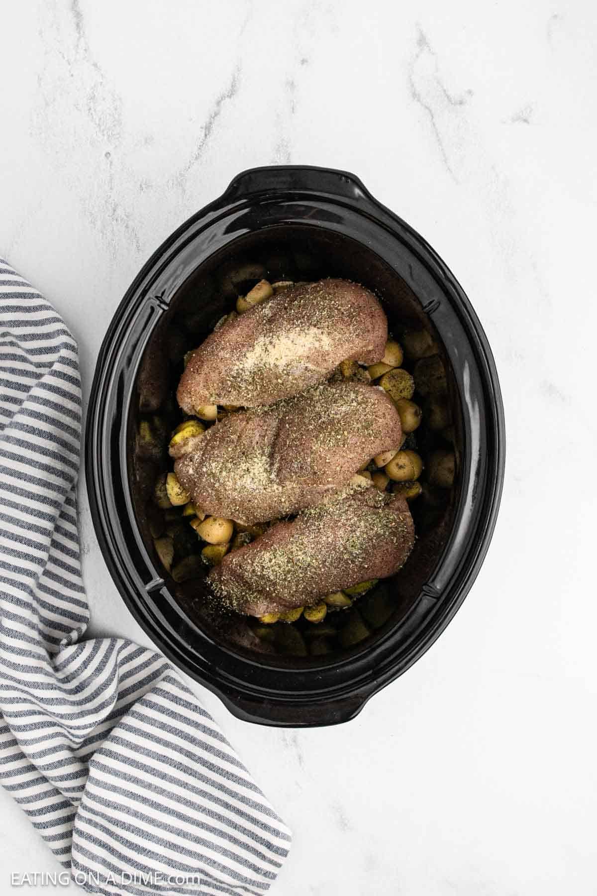 Seasoning added to raw chicken breast over the diced potatoes in the crock pot.