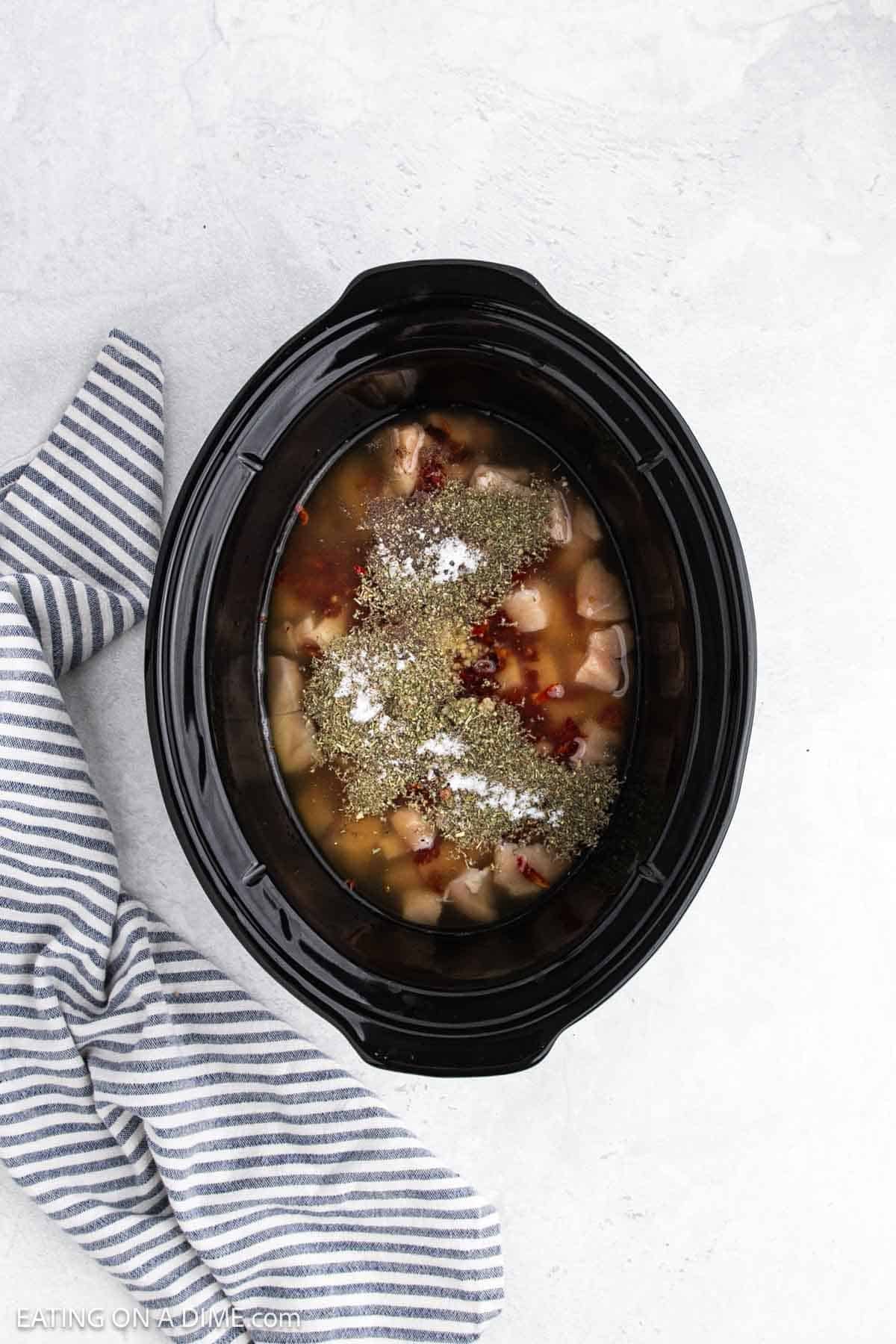 Chicken, broth and spices added to the slow cooker.