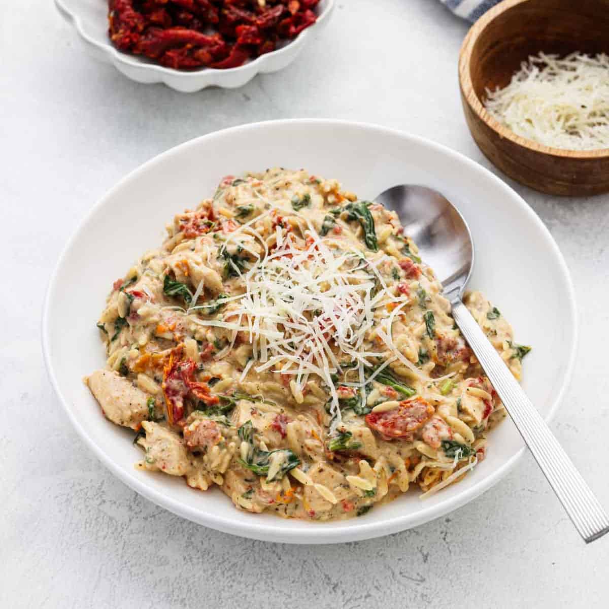 A serving of Chicken Orzo in a bowl with a spoon on the side.
