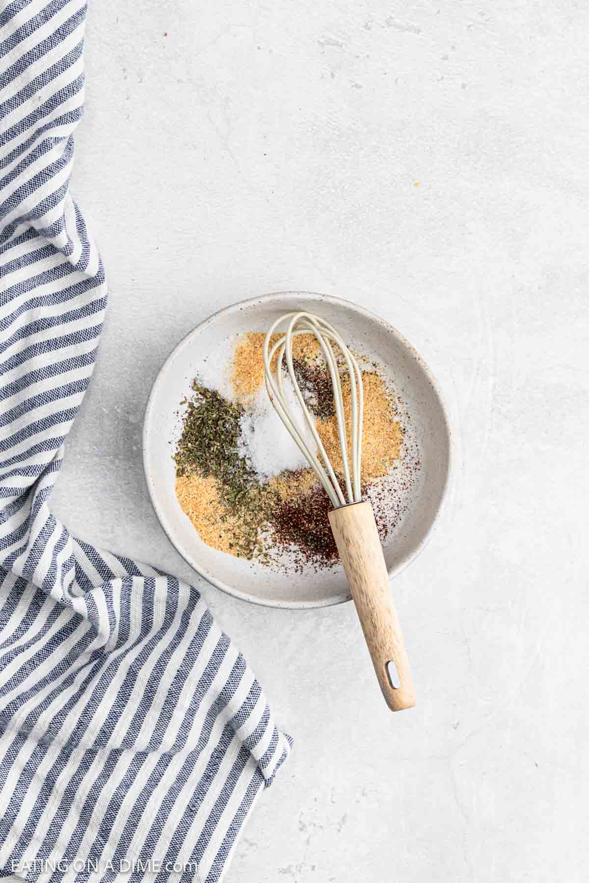 Combining the spices together in a small bowl with a whisk.