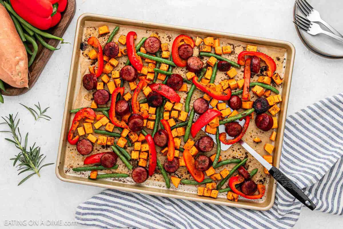 Sheet Pan Sausage and Veggies with a silver spatula on the baking sheet.