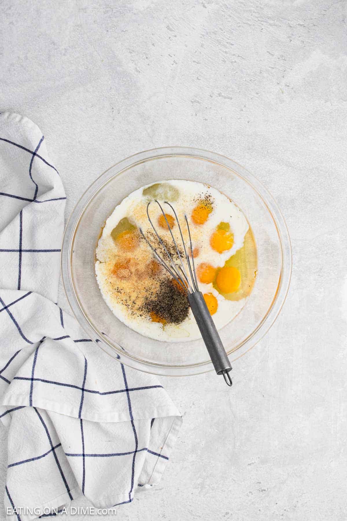 Whisking together milk, eggs, and spices in a bowl.