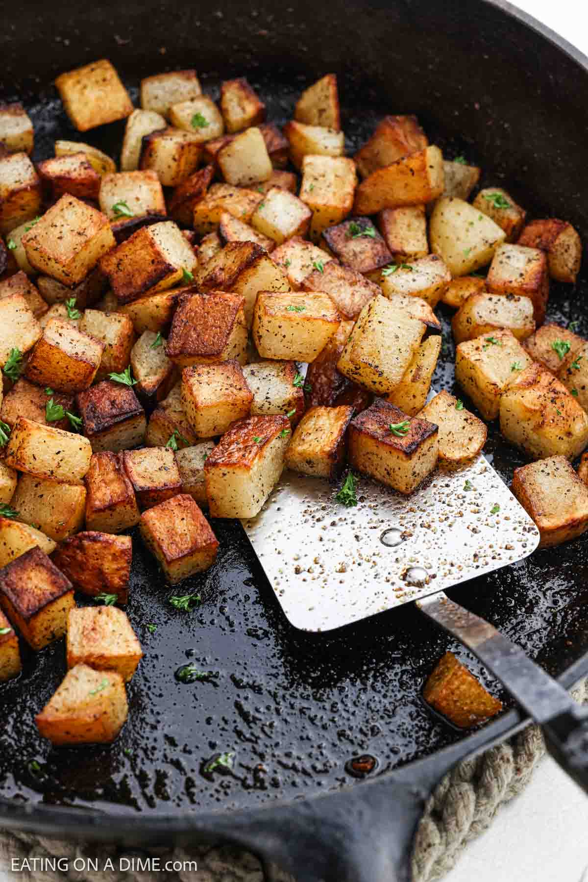 Golden and crispy breakfast potatoes in a cast iron skillet with a spatula.