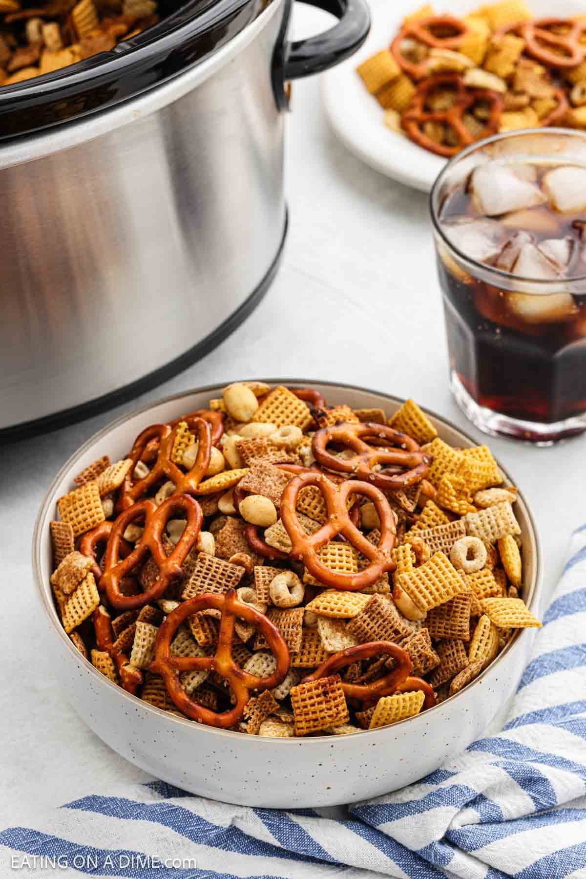 Chex Mix in a bowl with a glass of Coke nearby.