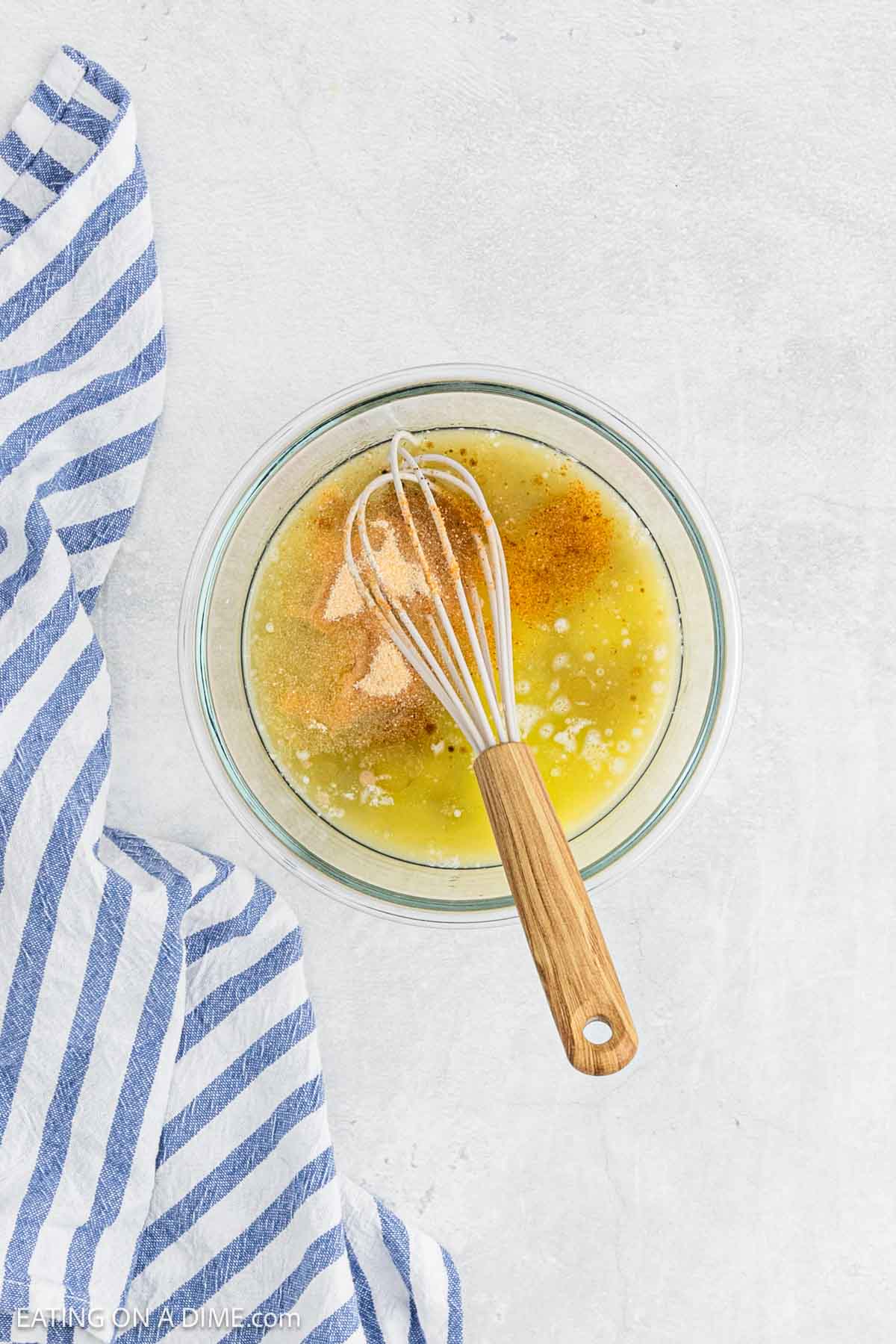 Combining the melted butter and spices in a bowl with a whisk.