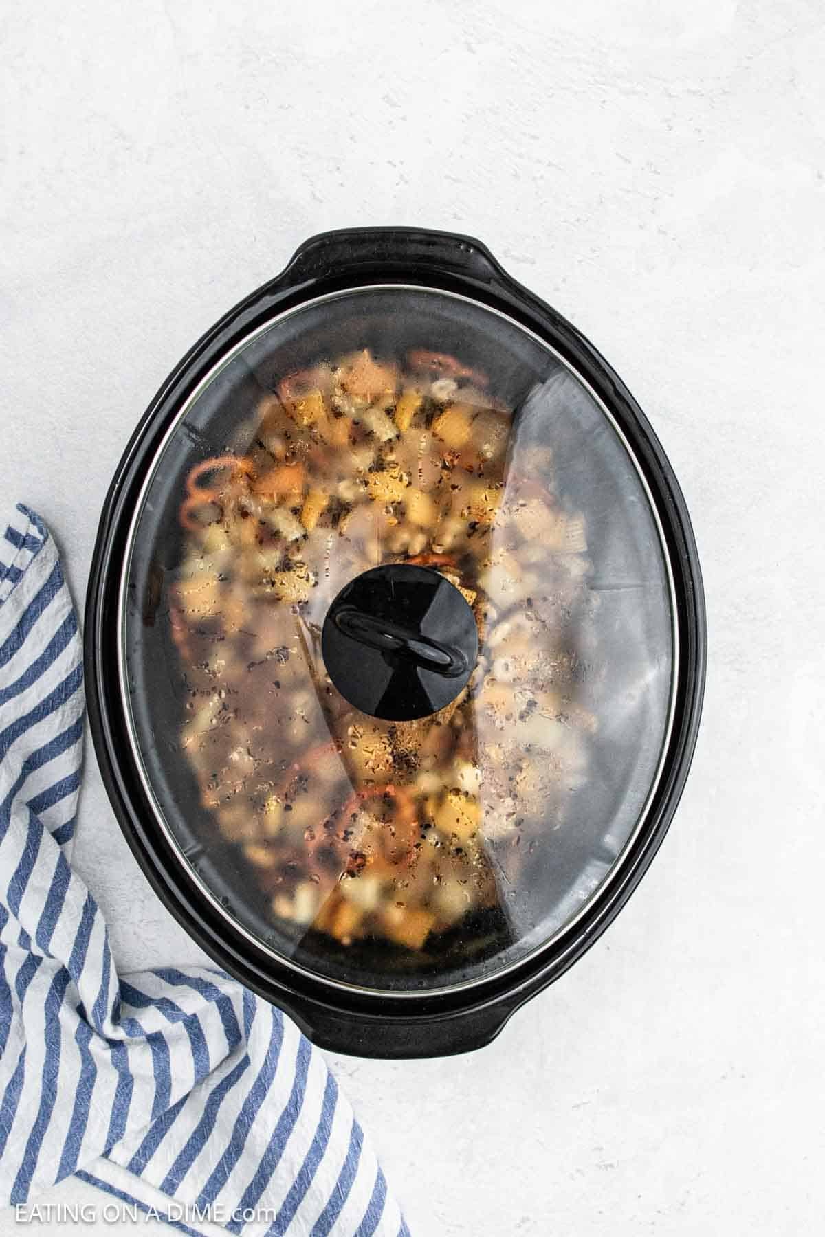 Putting the lid on the slow cooker with the recipe mixture inside.