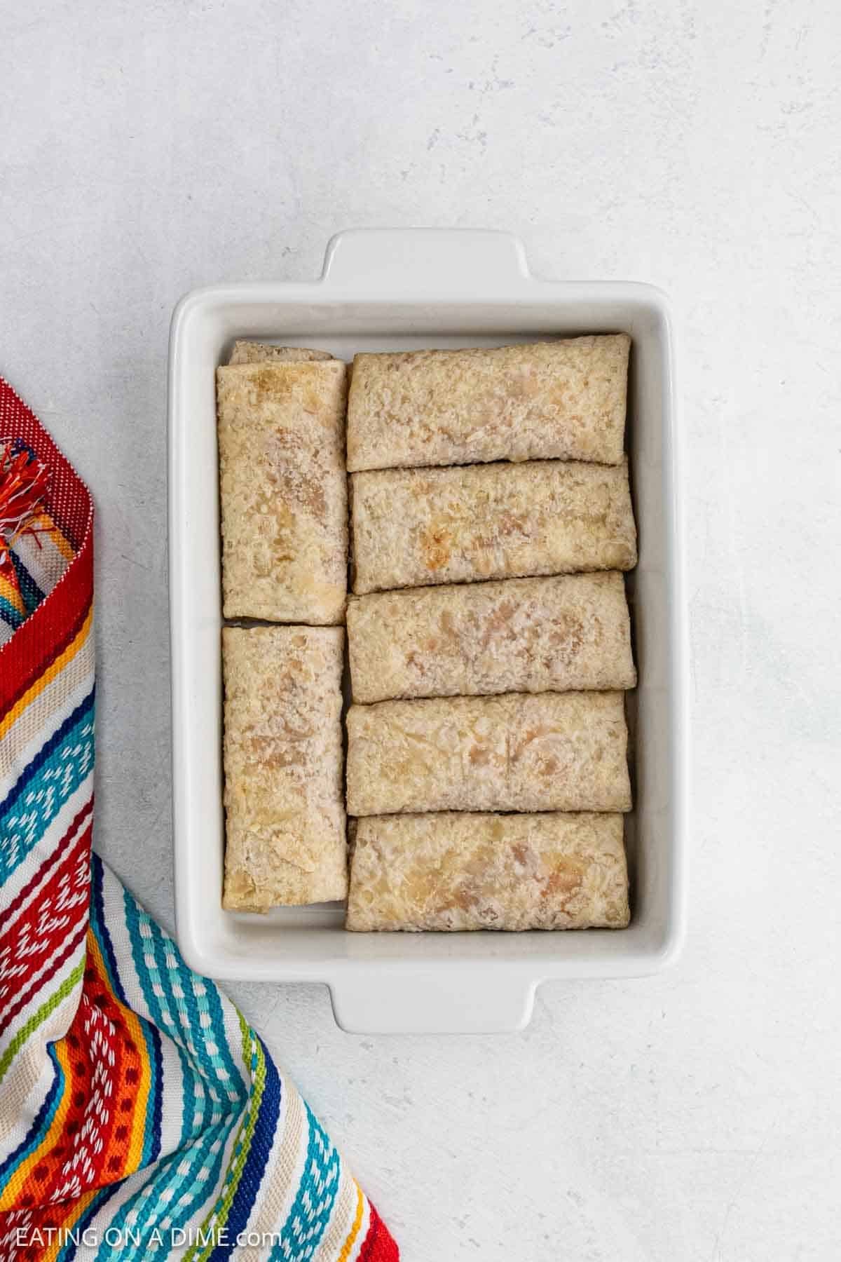 Placing frozen burritos in the casserole dish.