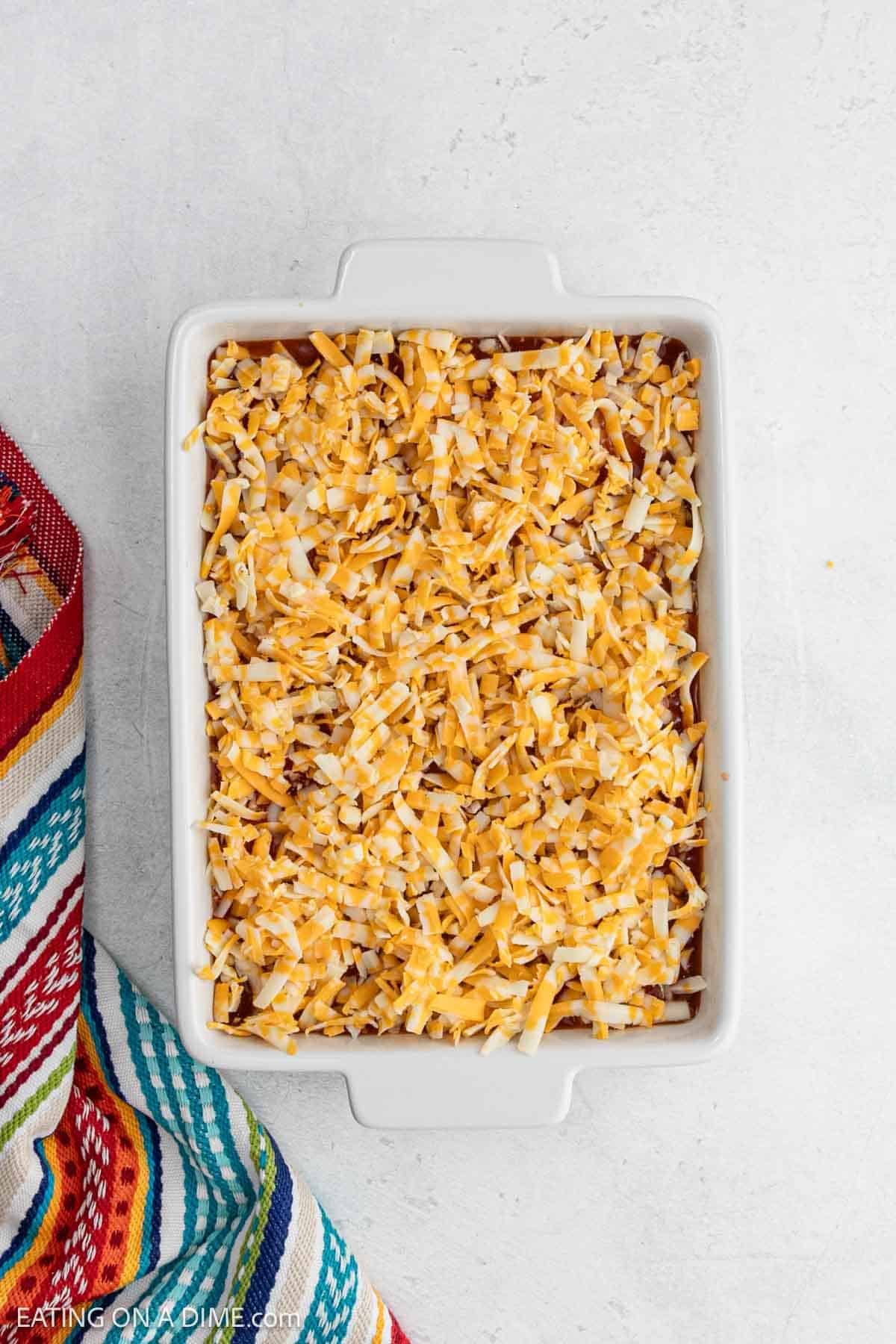 Shredded cheese added to the top of the ingredients in the baking dish.