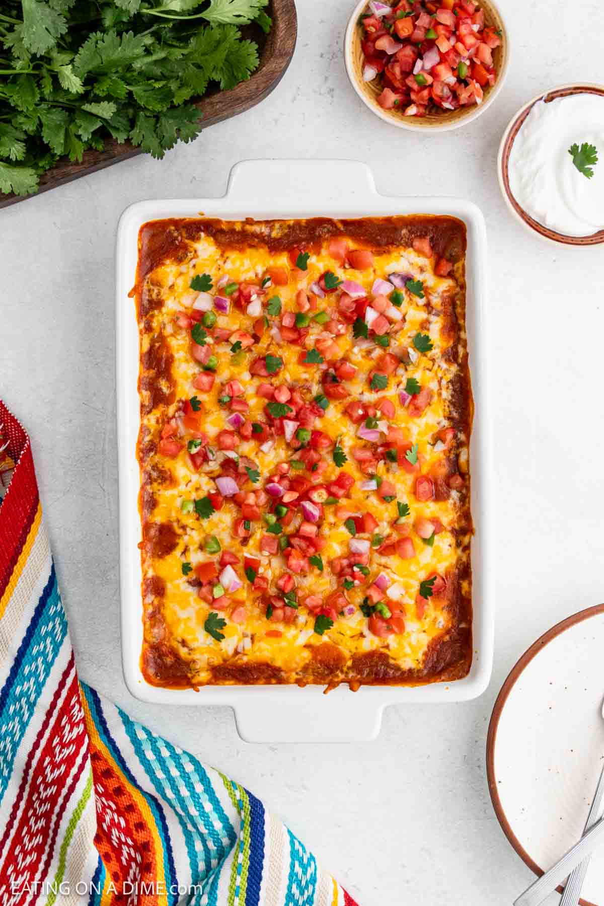 Baked casserole topped with melted cheese and pico de gallo in a baking dish.
