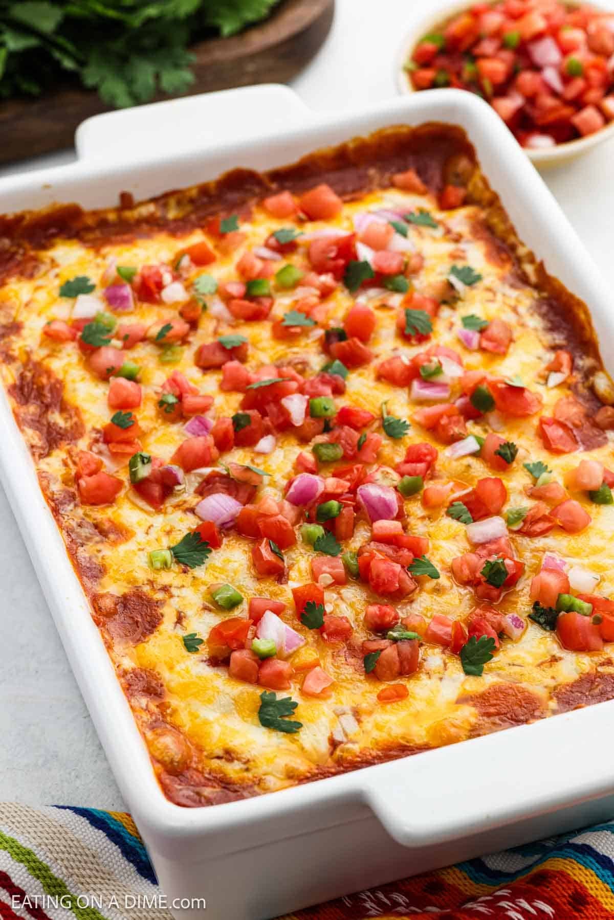 Baked casserole in a baking dish topped with melted cheese, pico de gallo, and chopped cilantro.