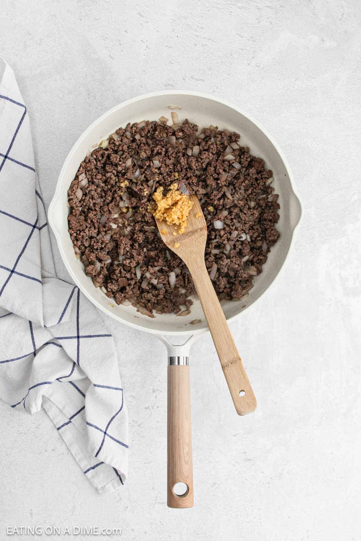 Cooked ground beef in a skillet with minced garlic.