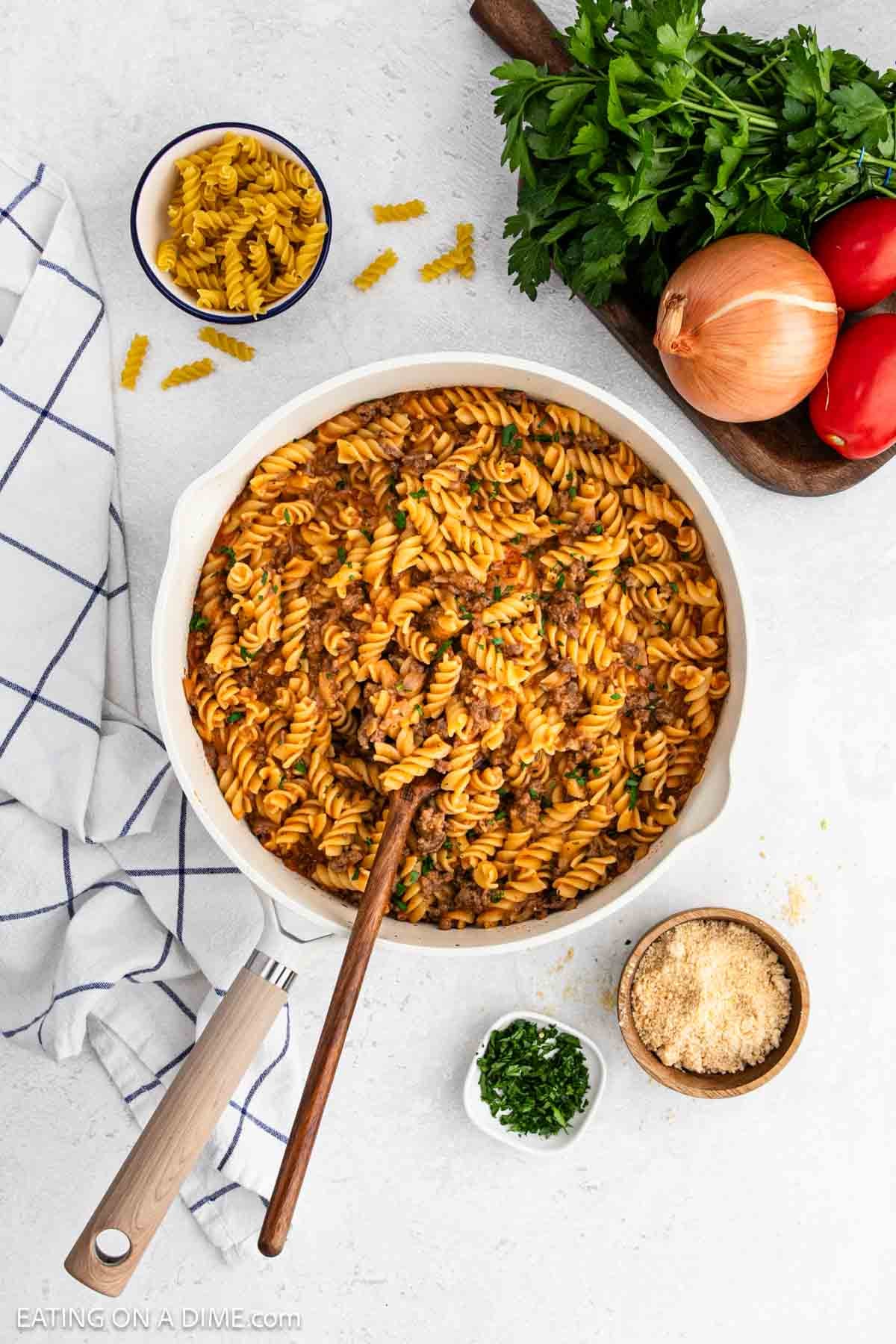 Creamy pasta and ground beef mixture in a skillet with a wooden spoon.