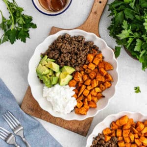 Ground, diced sweet potatoes, avocado, and cottage cheese placed in a bowl.