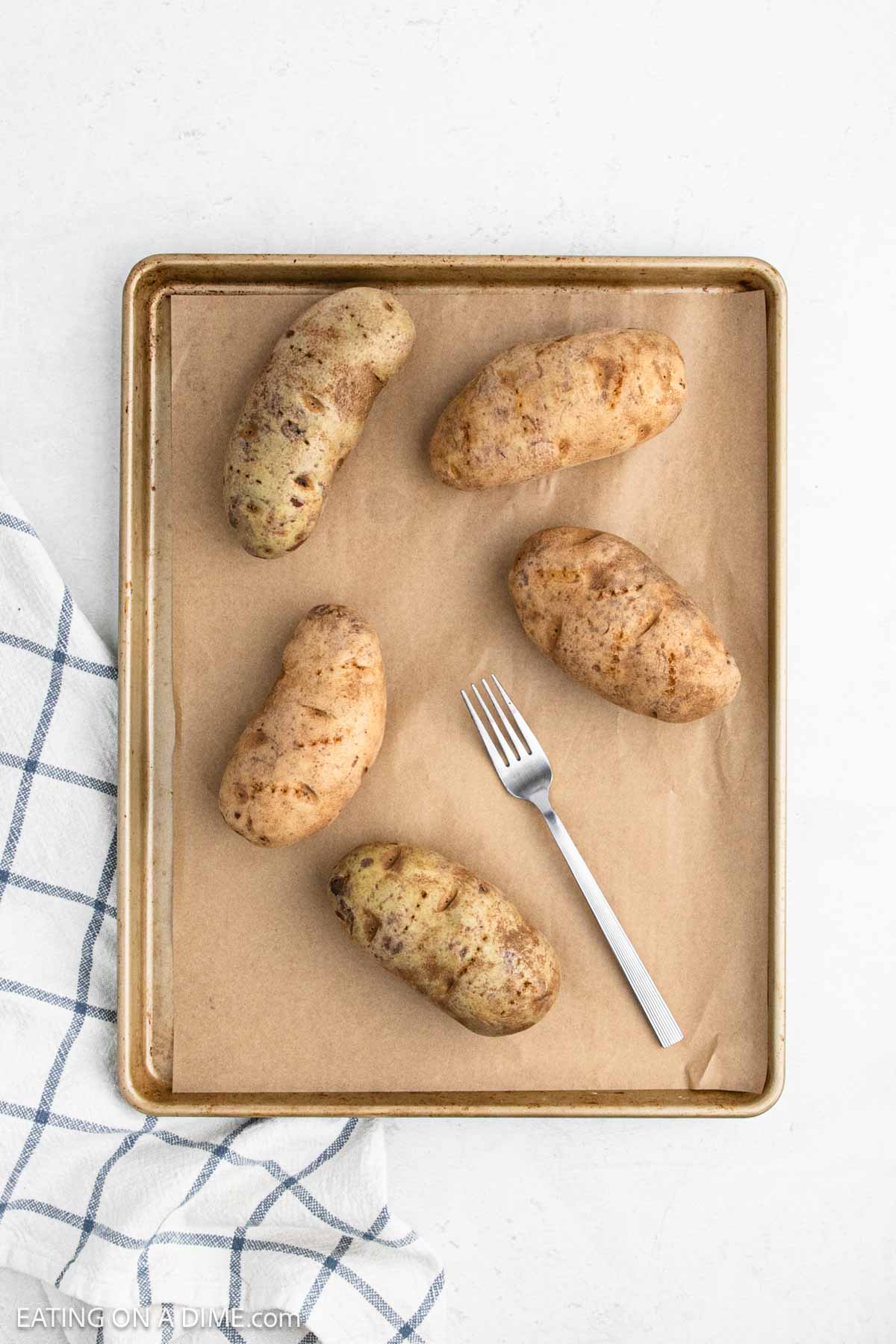 Russet potatoes on a baking sheet lined with parchment paper.