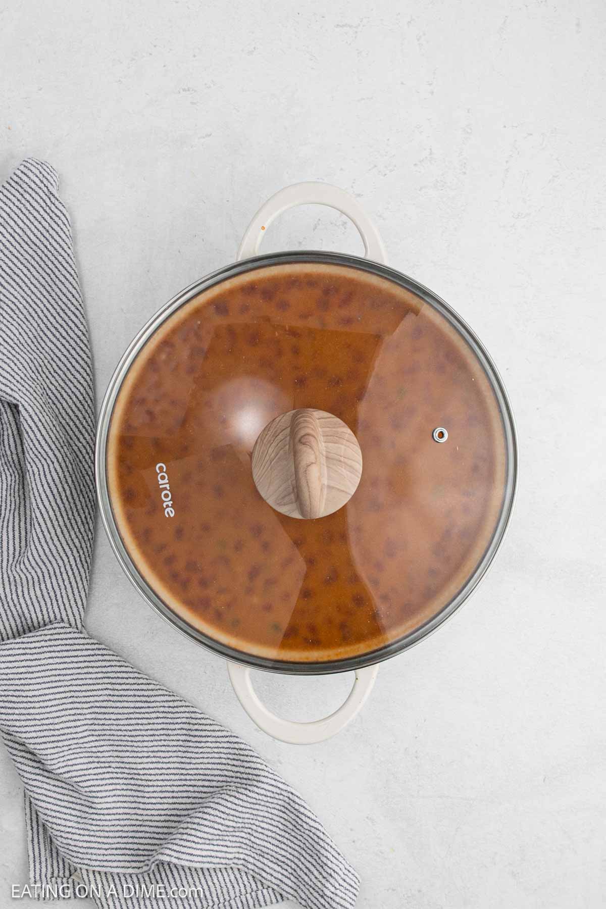 Large pot with a lid covering the recipe ingredients.