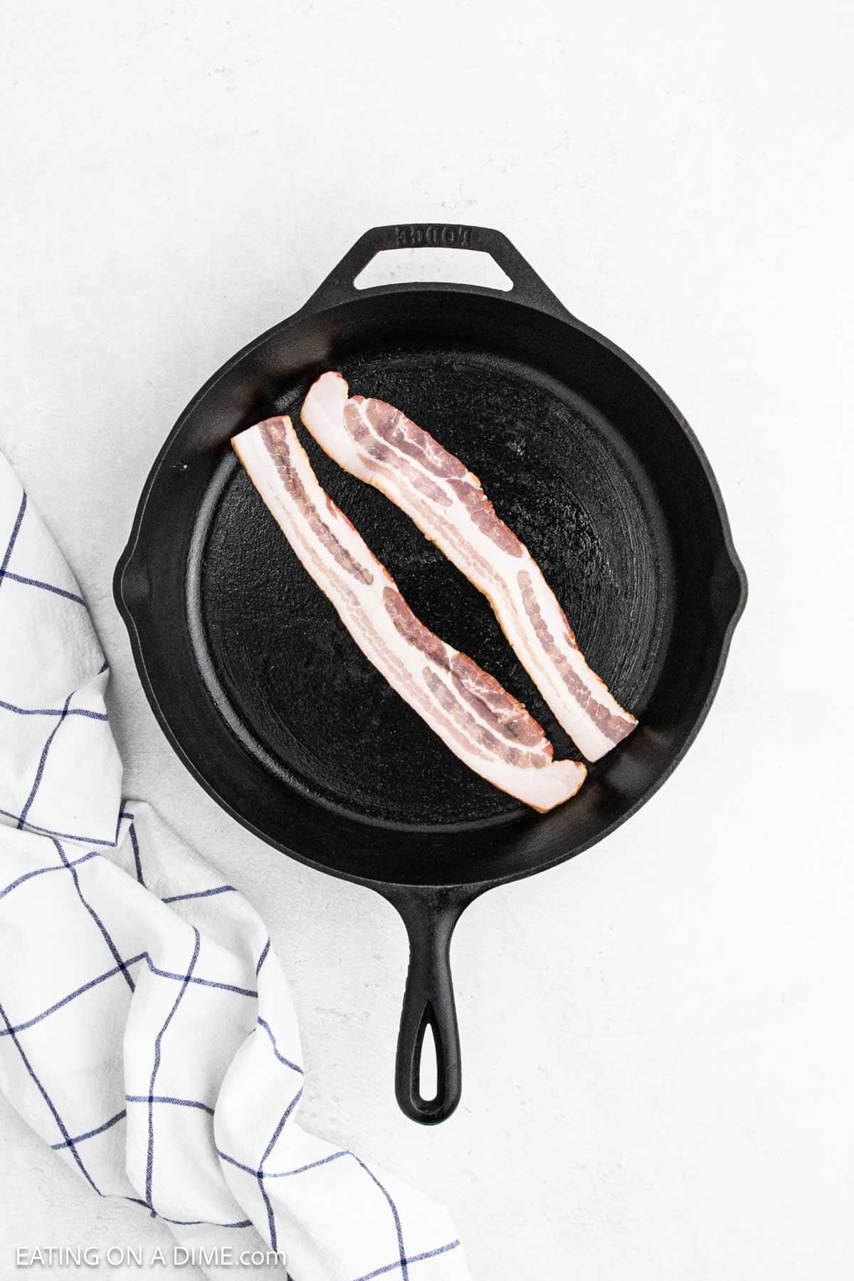 Slices of bacon in a cast iron skillet.