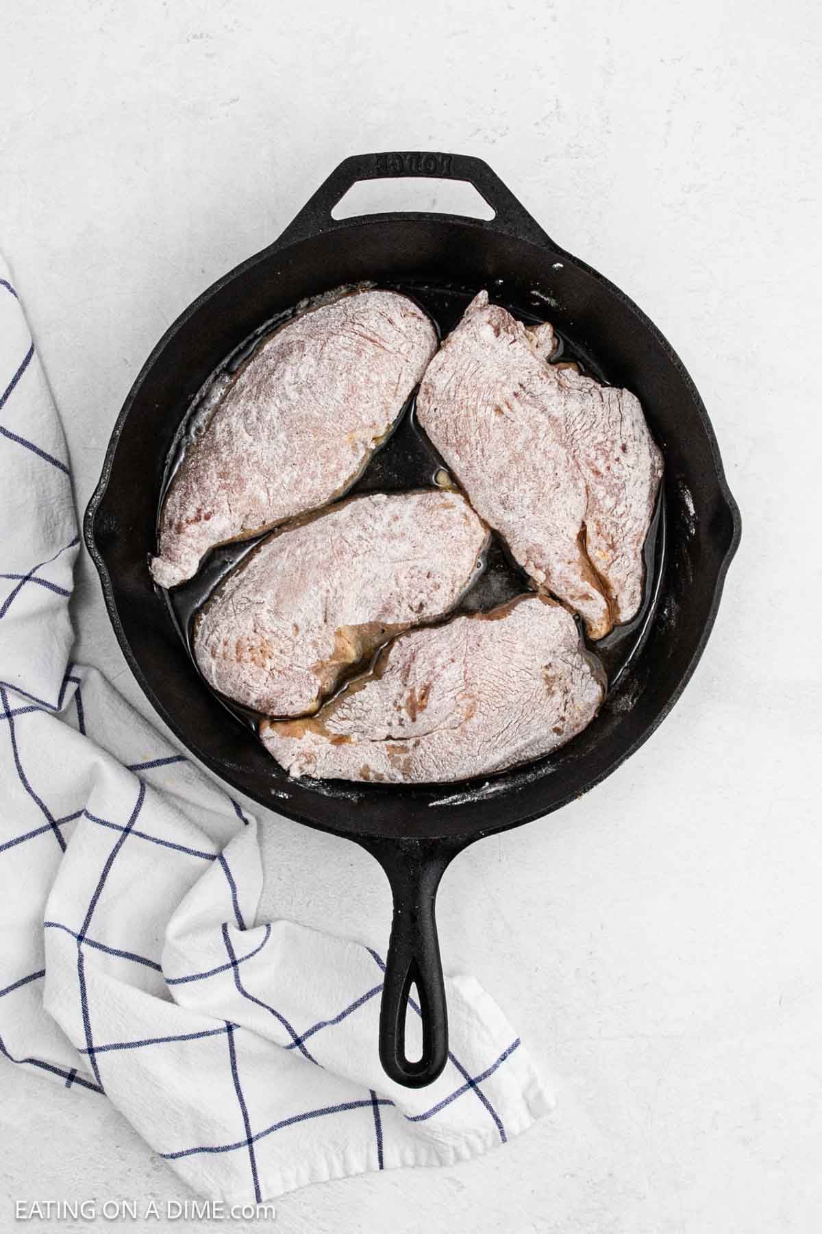 Place floured chicken breast in a cast iron skillet with melted butter.