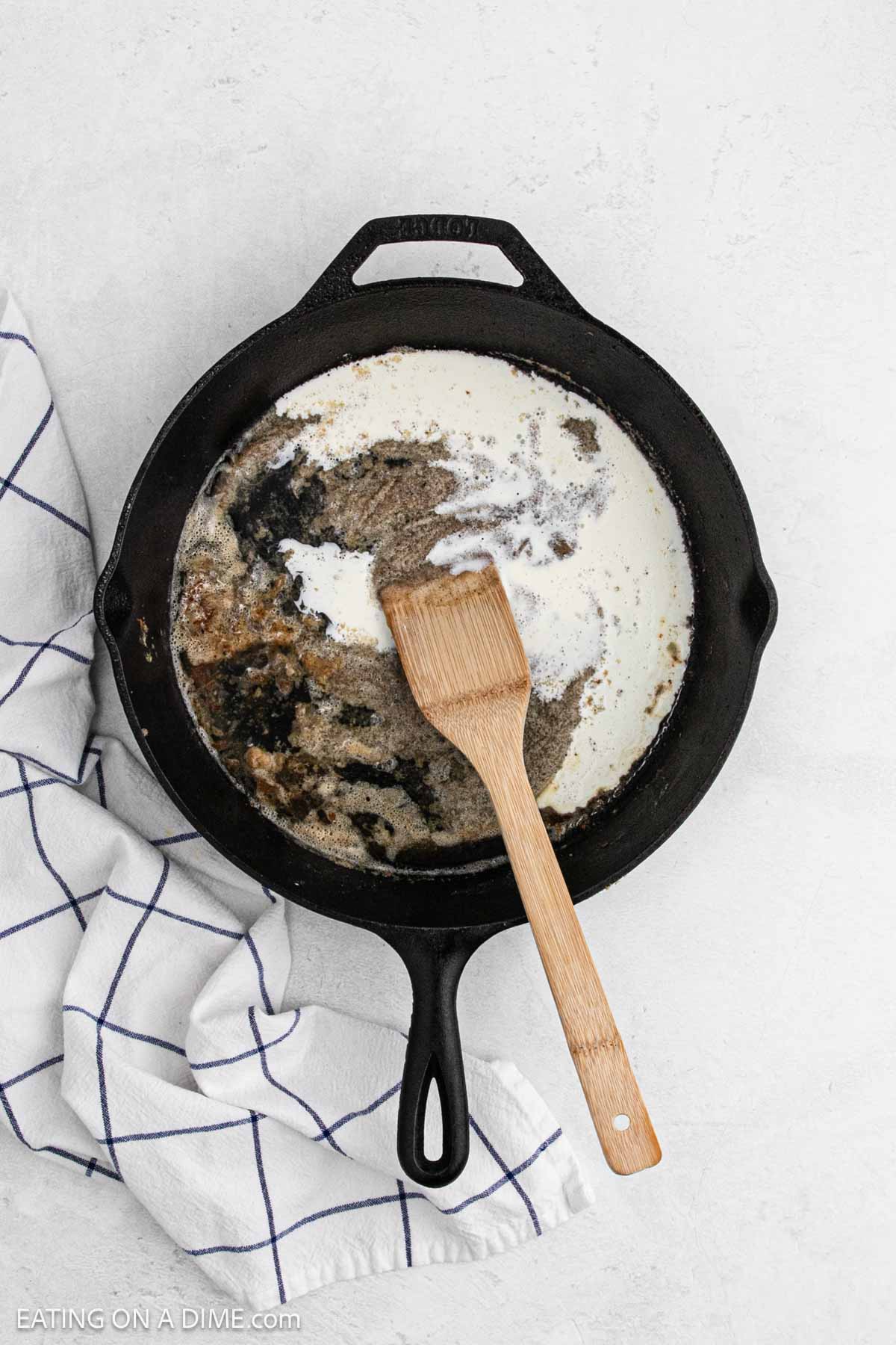 Mixing in the heavy cream with the roux mixture in a cast iron skillet.