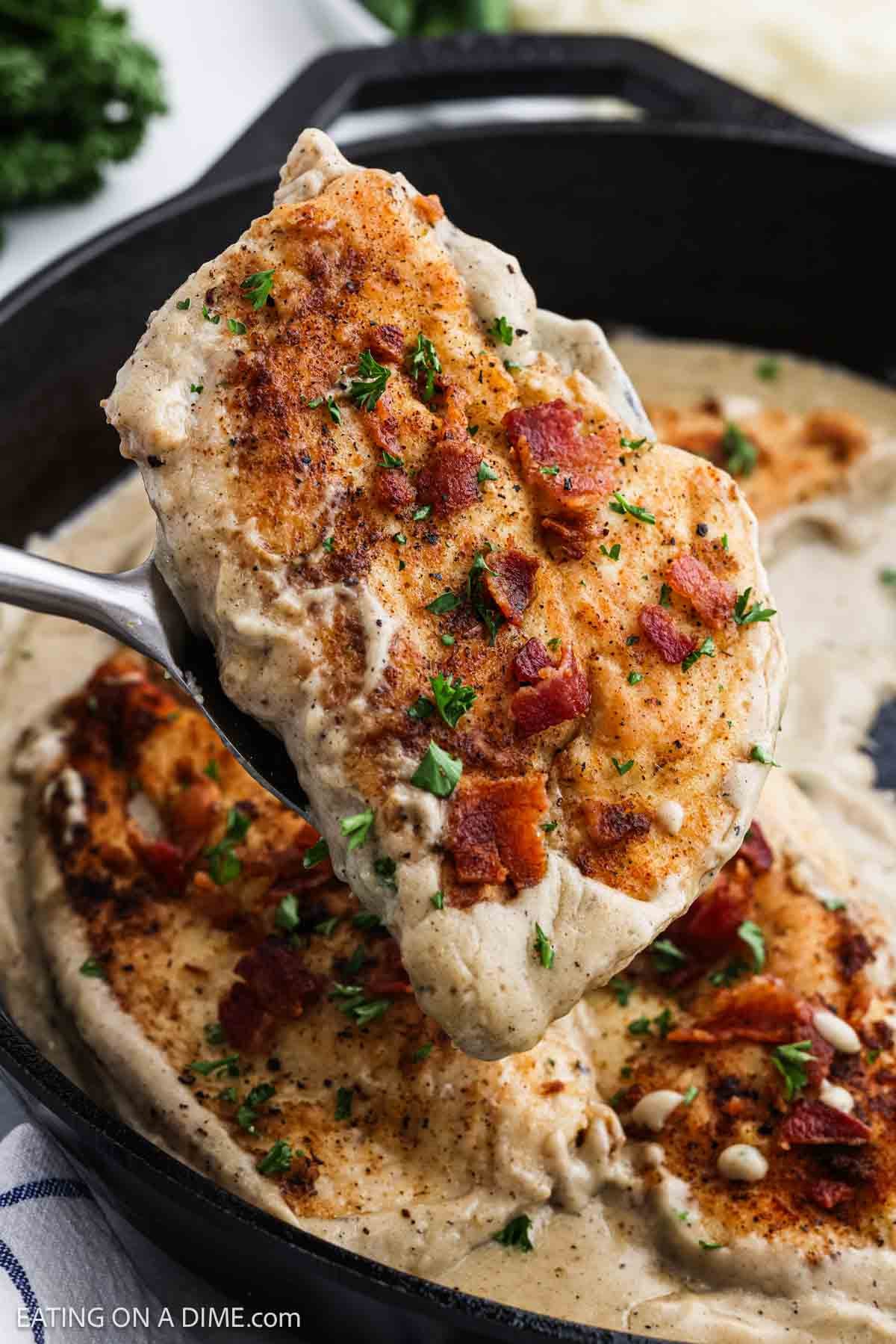 Close up image of golden brown chicken topped with crispy bacon with gravy.