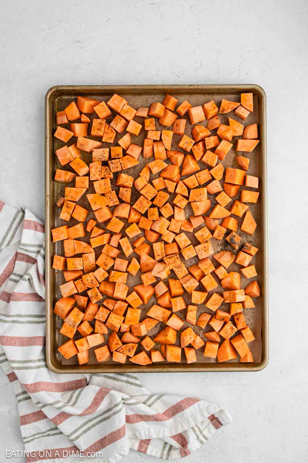 Diced sweet potatoes spread on a baking sheet.