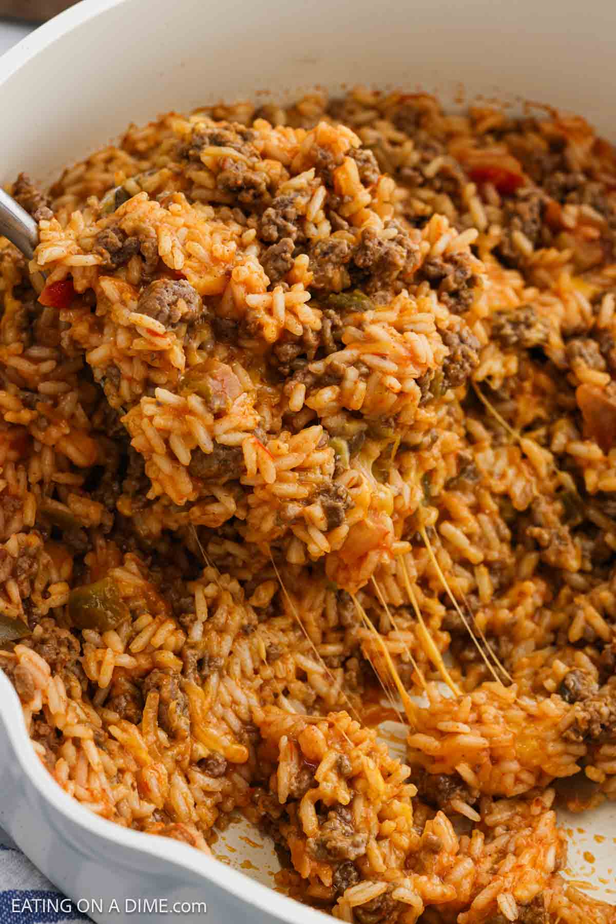 Close up image of ground beef, rice, and melted cheese mixed together in a skillet.
