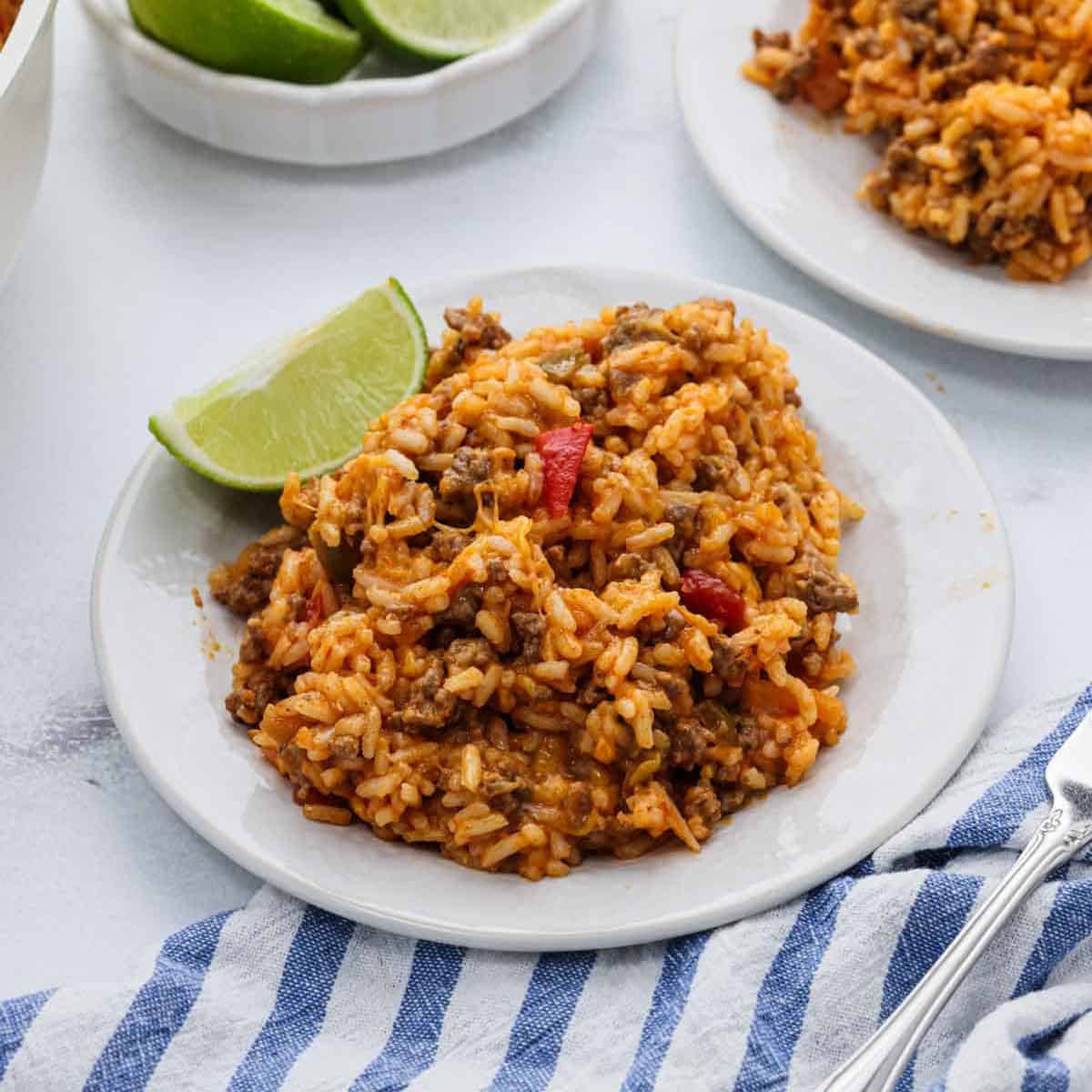 A serving of taco rice on a plate with a side of lime wedge.