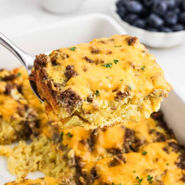 A serving of the Tater Tot Breakfast Casserole on a spatula over a baking dish.