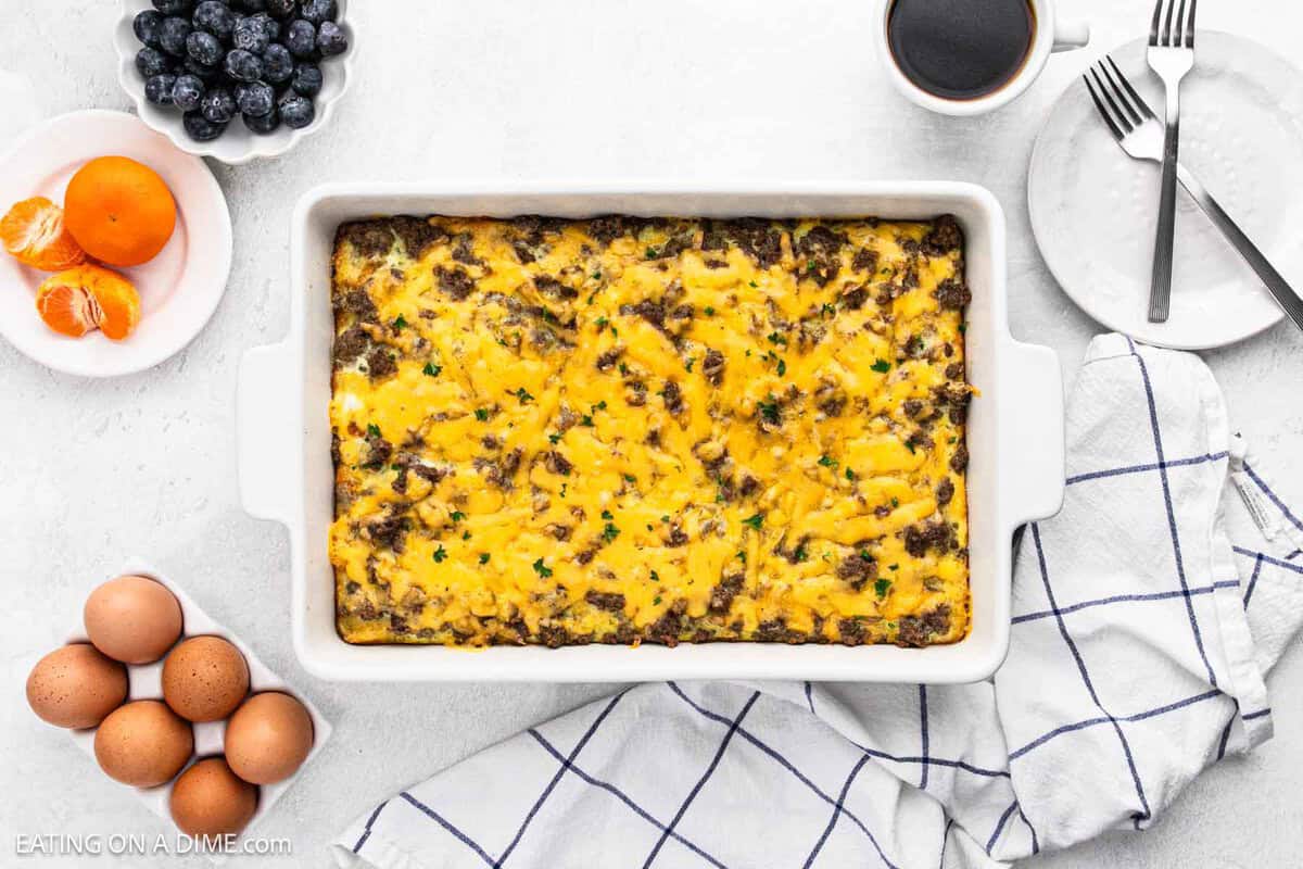 Tater Tot Breakfast casserole in a baking dish with a side of eggs, orange and a bowl of blueberries on the side.