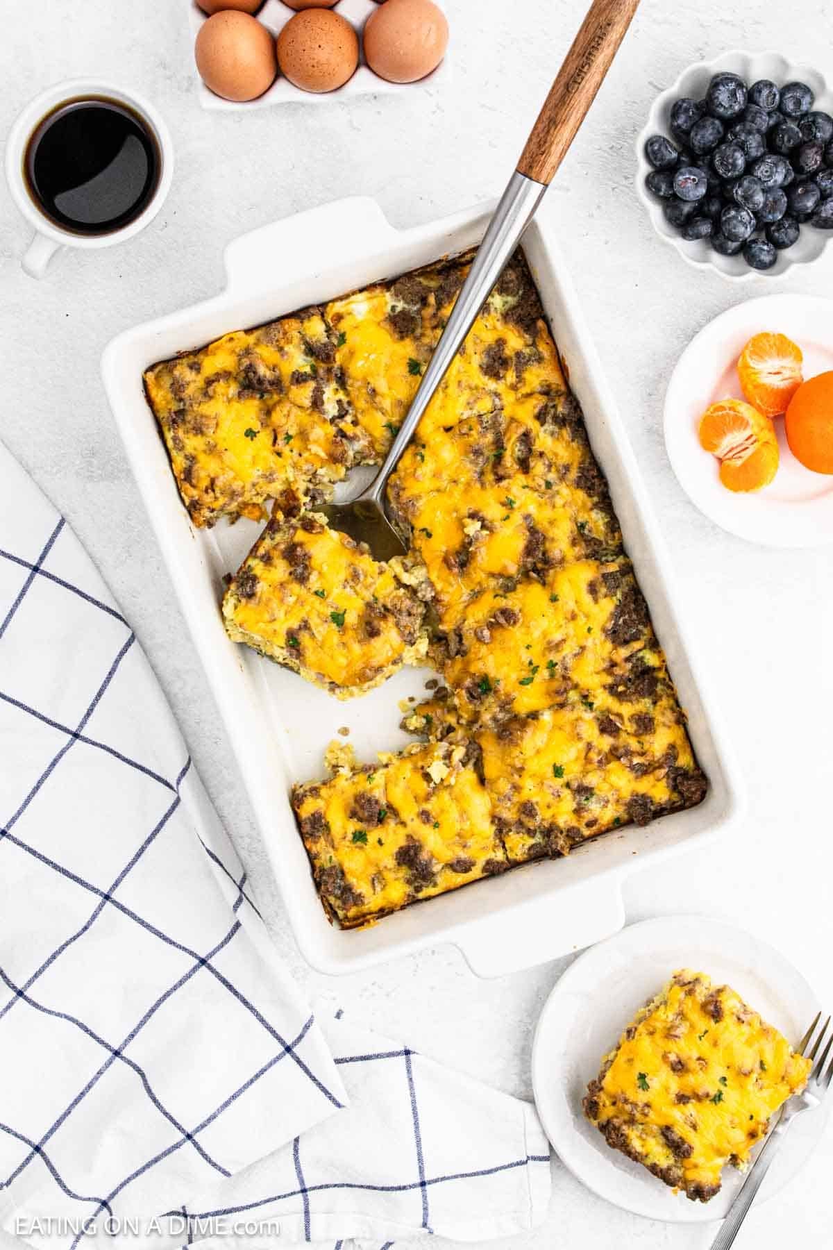 Breakfast casserole in a baking dish with a serving on a spatula with a serving on a plate nearby.
