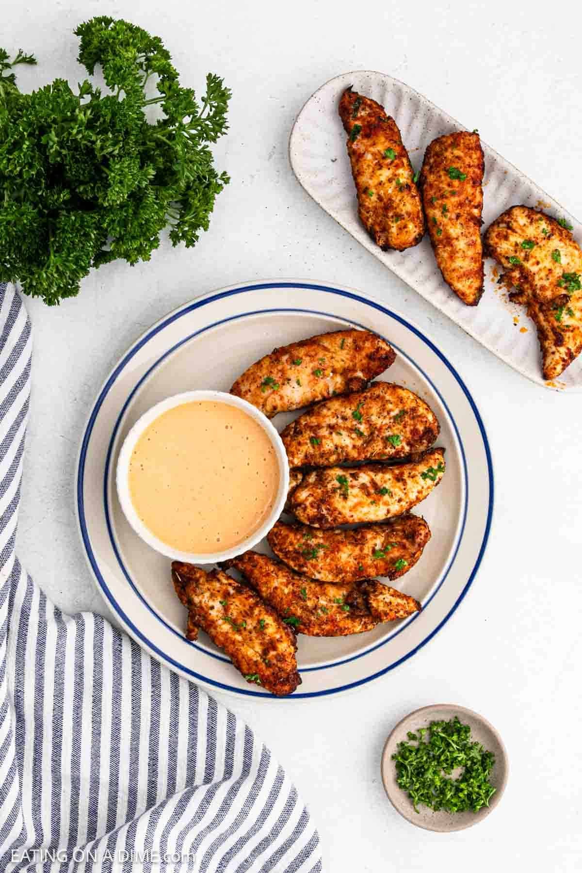 Cooked chicken on a platter with a bowl of sauce nearby.